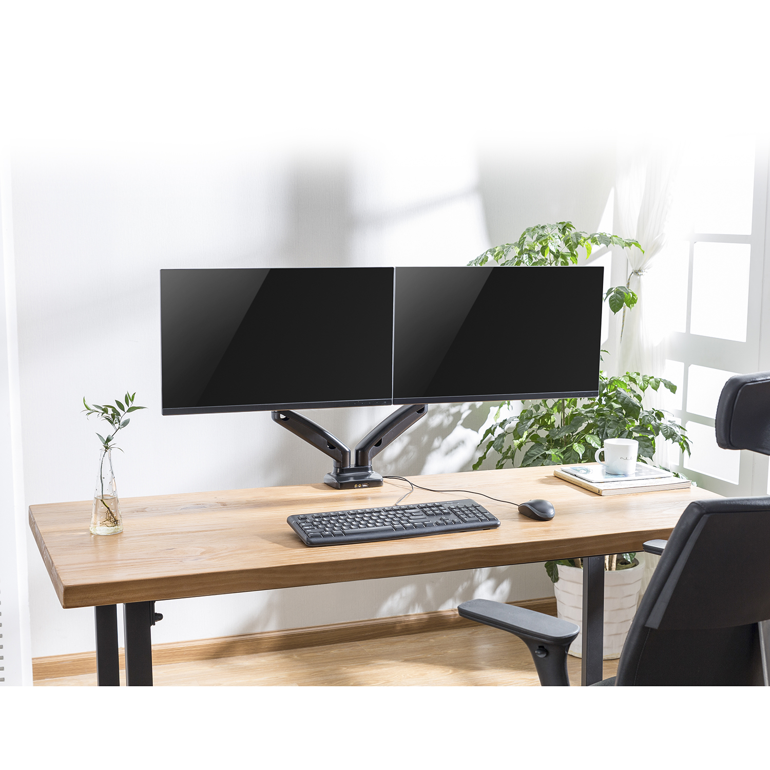 Two monitors mounted on an arm, with a keyboard and mouse on a wooden desk.