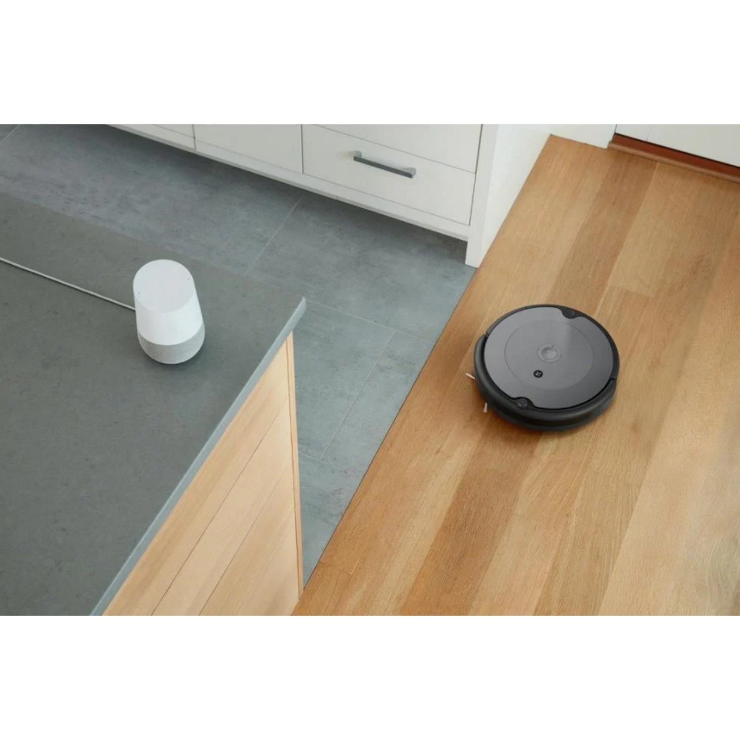 Dispositivos domésticos inteligentes: una aspiradora robot y un altavoz Google Home blanco.