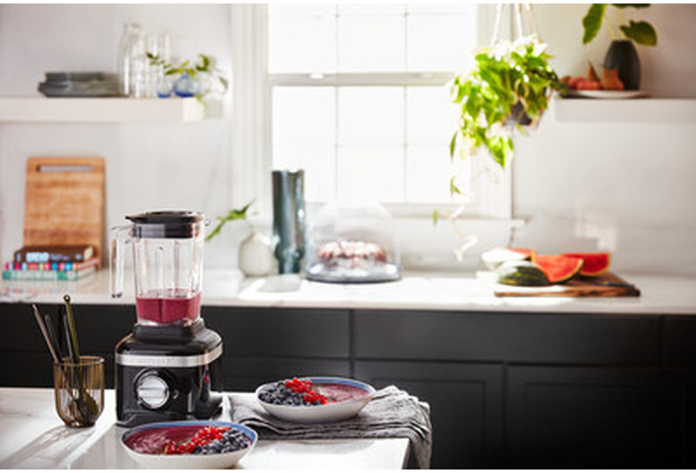 Keuken met een blender en twee kommen bessen op een aanrecht. Een raam op de achtergrond.