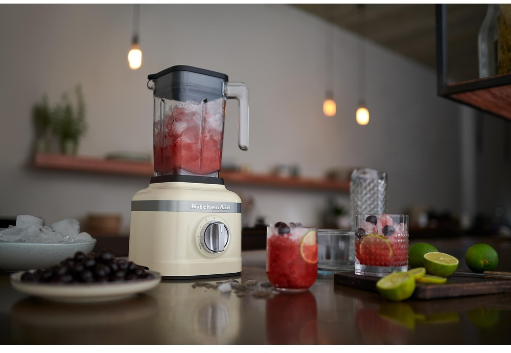 Blender met ijs en rode drank. Drankjes in glazen, limoenen op de toonbank, gloeilampen boven.