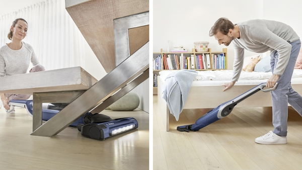 People vacuuming. One under stairs, the other under a bed, with a blue vacuum.