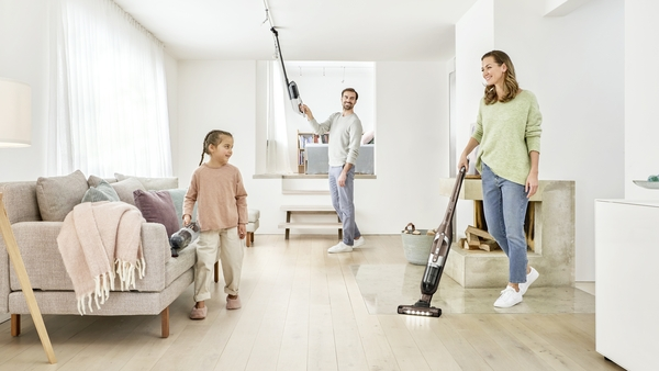 Family vacuuming a room. A woman and a girl are vacuuming on a white background.