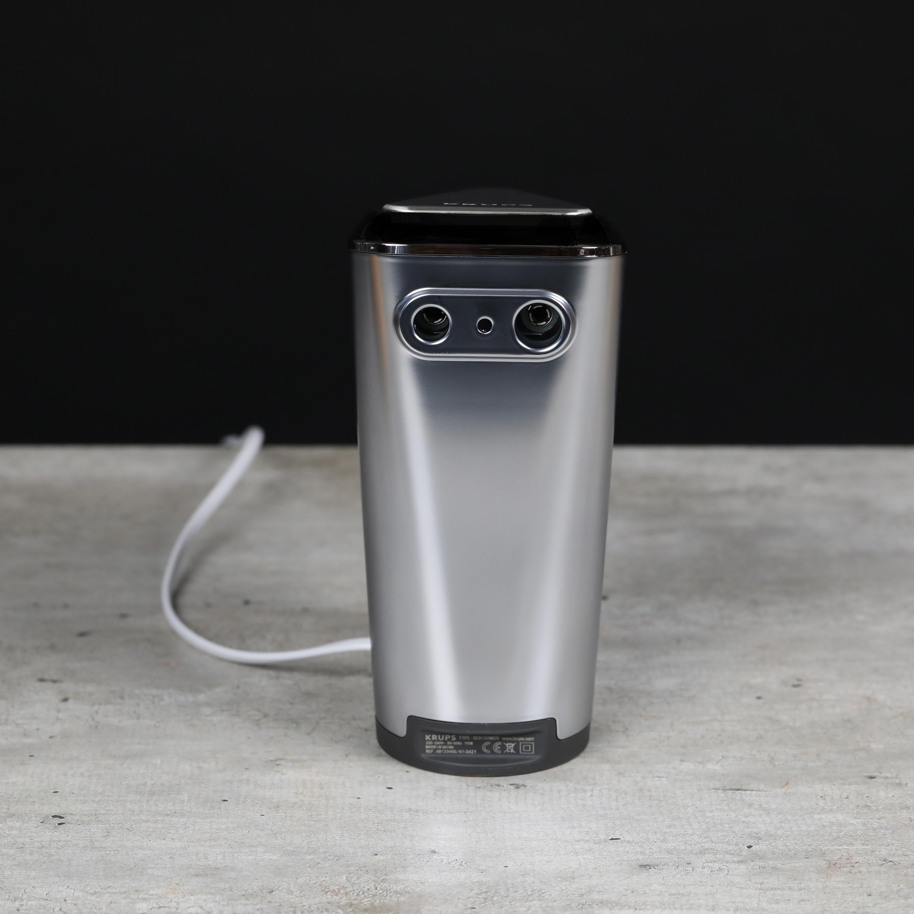 Eine Krups Kaffeemaschine. Sie ist silberfarben mit schwarzem Deckel und weißem Netzkabel.