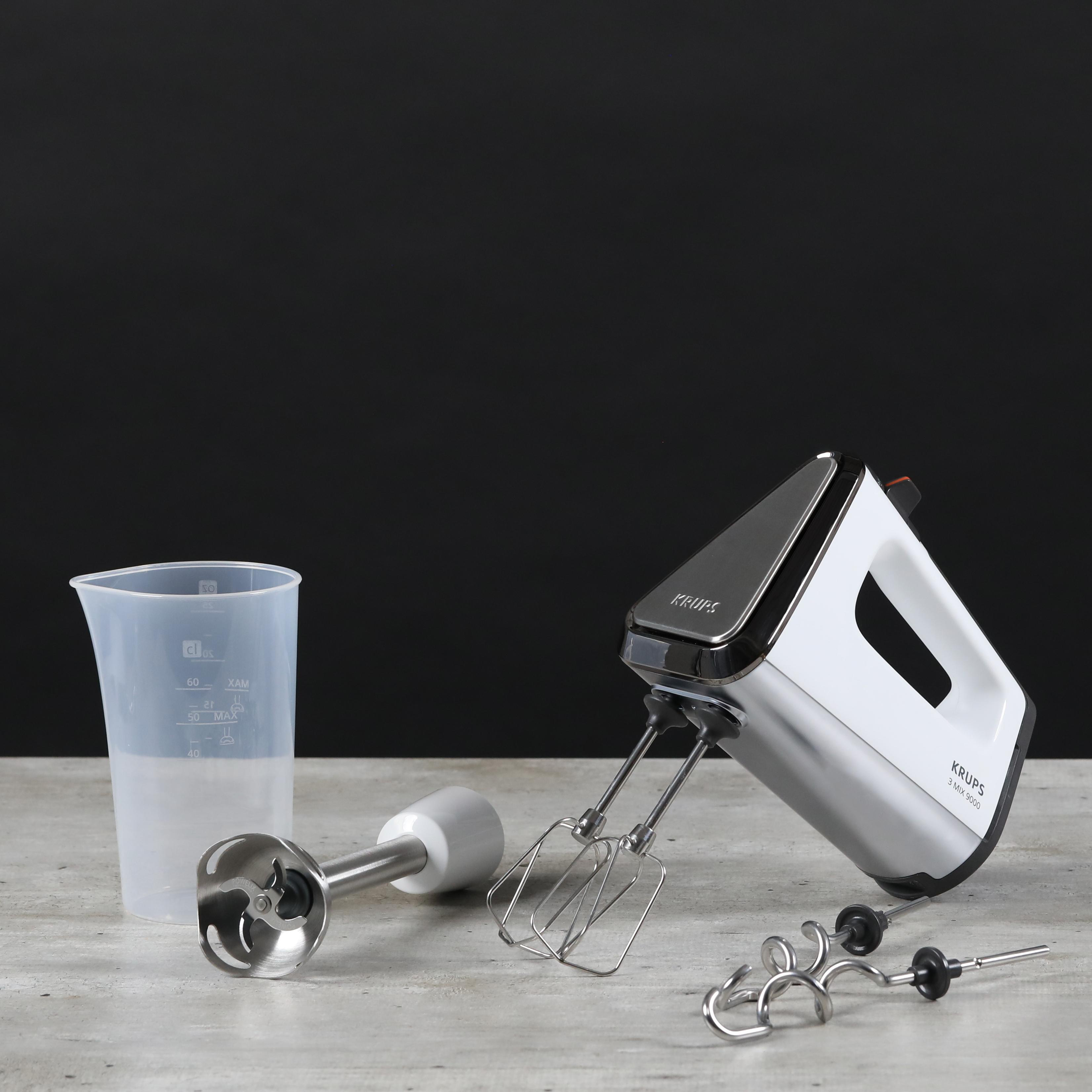 Ein weißer und silberner Handmixer mit Aufsätzen und einem Messbecher.