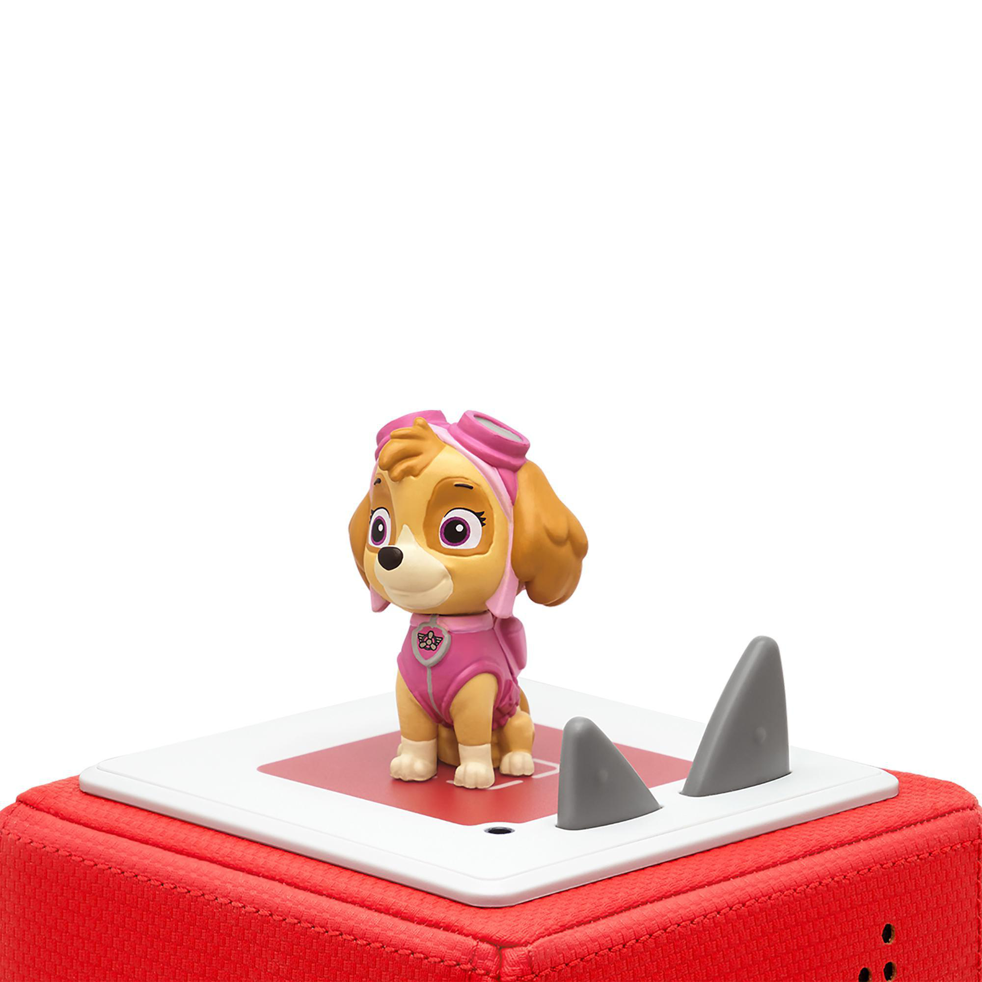 Paw Patrol Skye Figur auf einer roten Box, mit zwei Haifischflossen, isoliert auf weißem Hintergrund.
