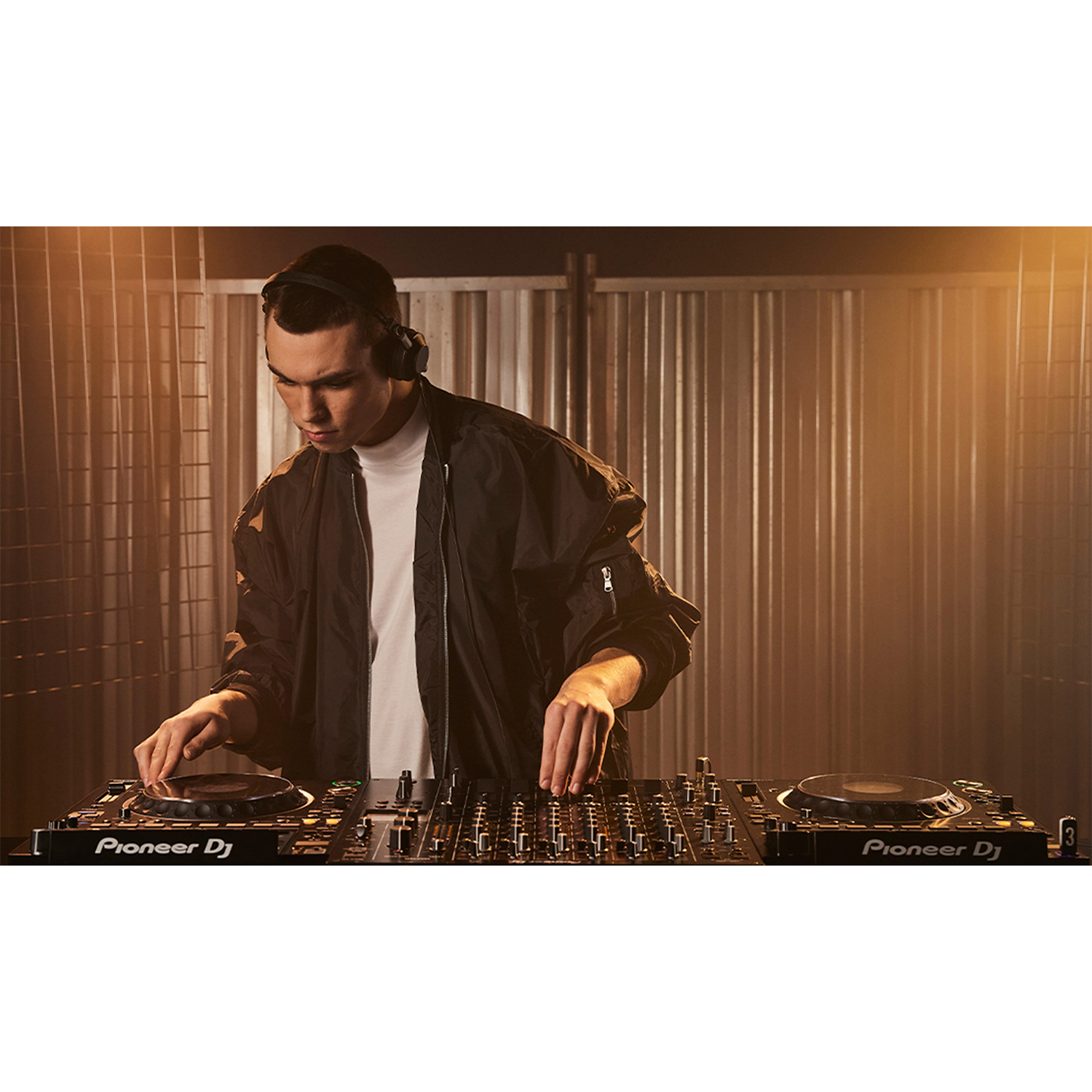 Un DJ al lavoro. Indossa le cuffie e mixa musica su una consolle.