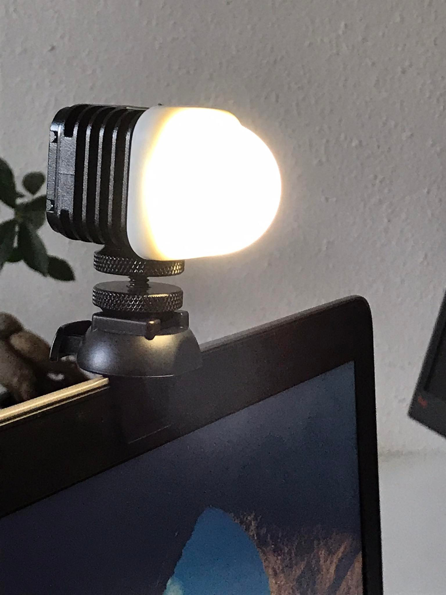 Egy kis fekete LED-lámpa van a laptop képernyőjének tetejére szerelve. A lámpa világít és élénken világít.