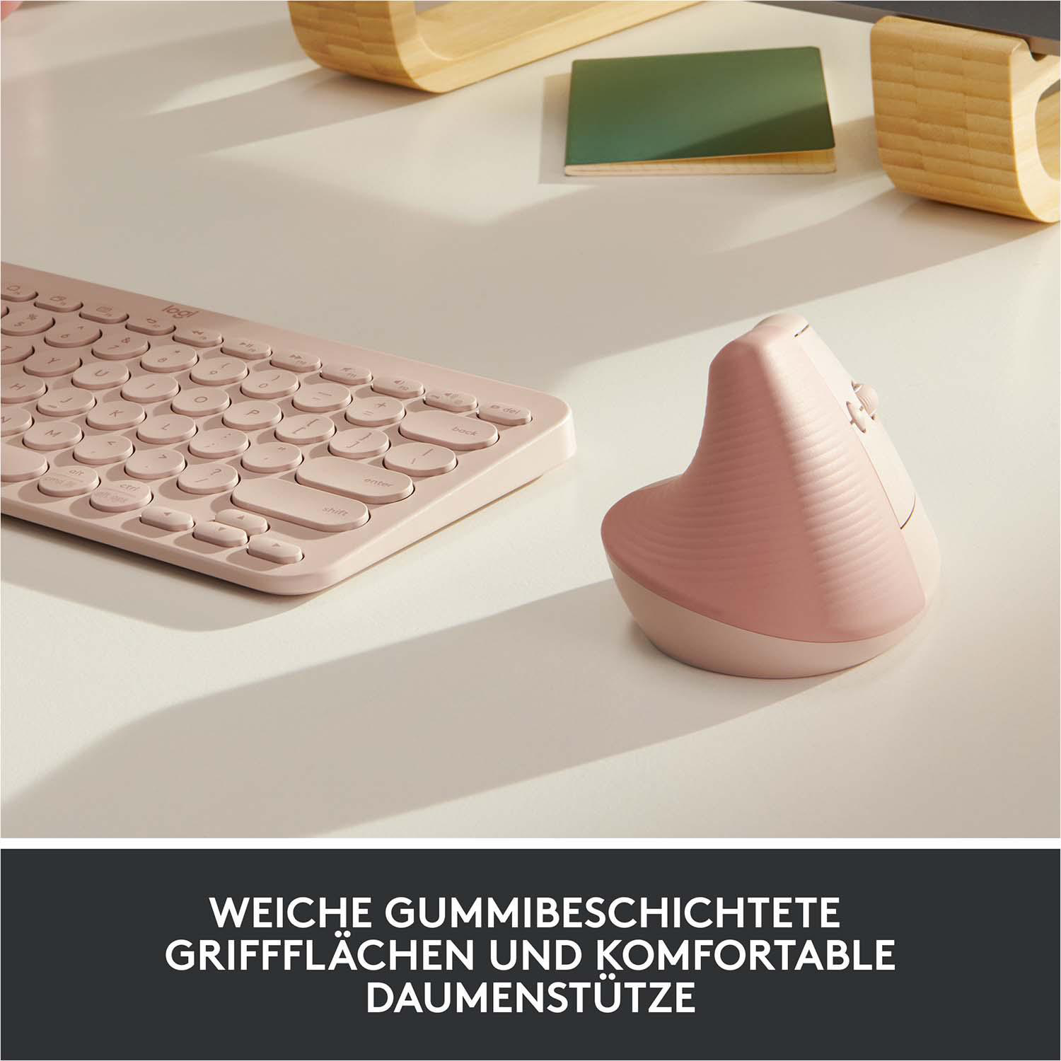 Rosa ergonomische Maus und Tastatur auf weißem Schreibtisch, darunter Text auf Deutsch.