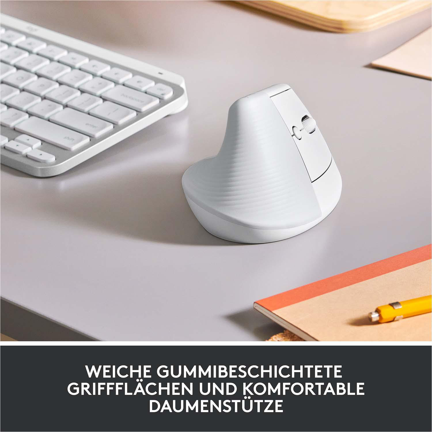 Weisse ergonomische Vertikalmaus auf grauem Schreibtisch mit Tastatur und Notizbuch.