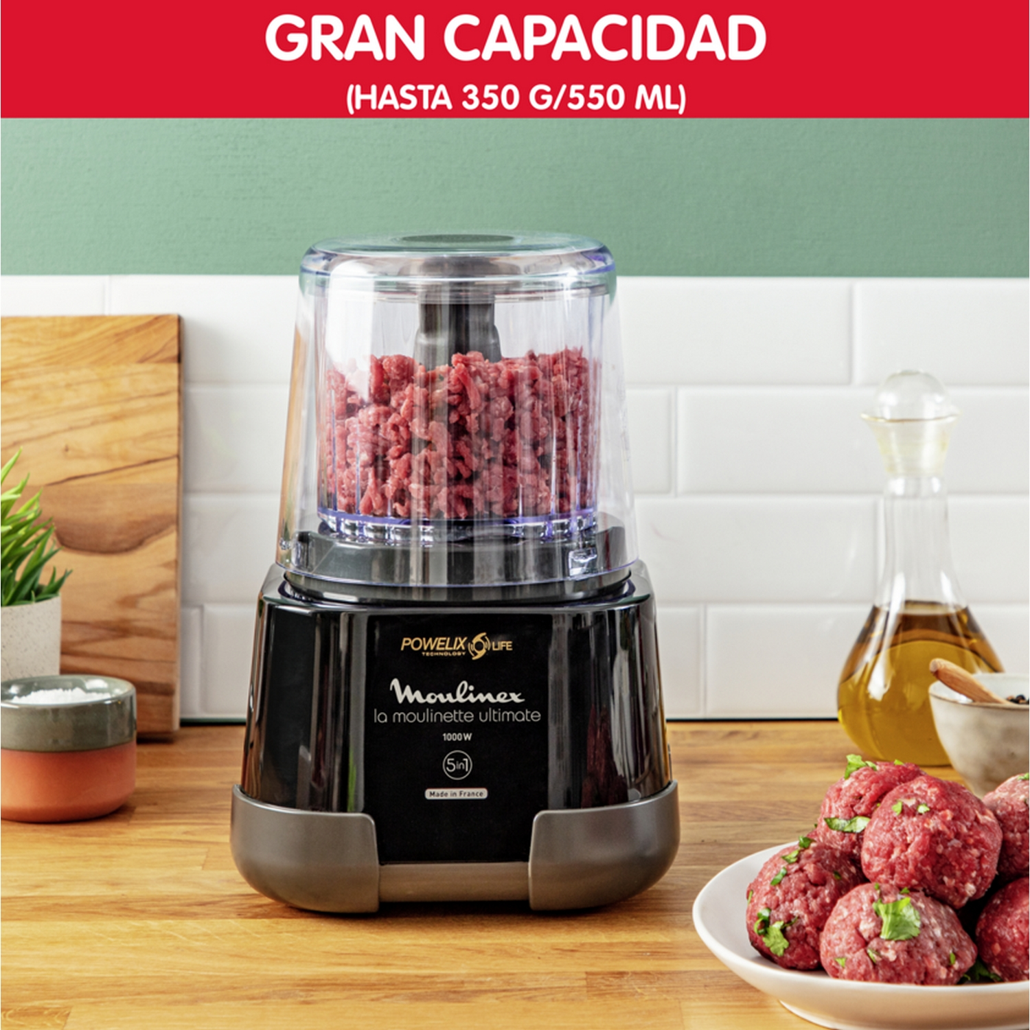 Picadora de alimentos Moulinex negra con carne dentro. También, albóndigas en un plato.