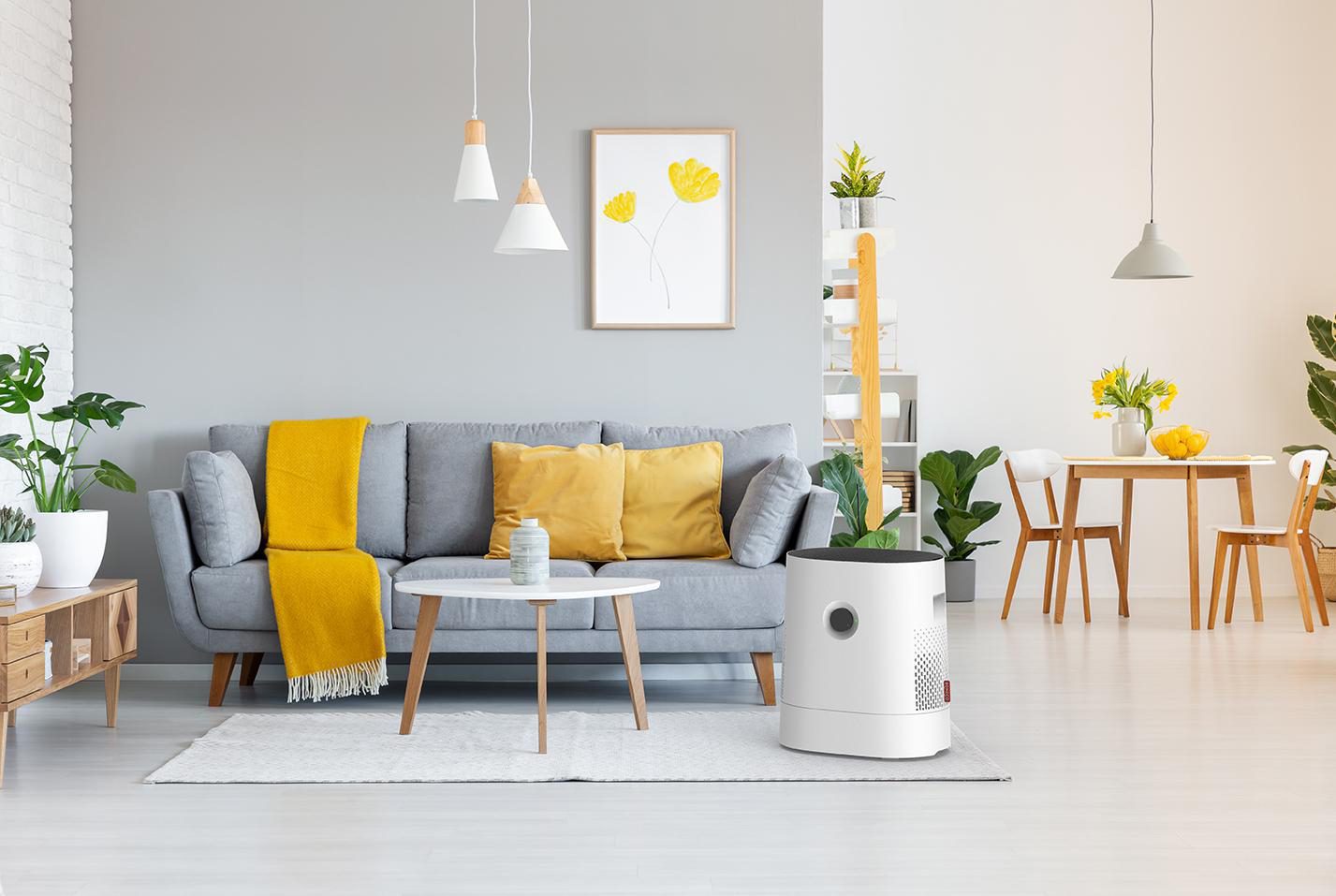 Interieur mit grauem Sofa, gelben Akzenten, Pflanzen und einem weißen Luftreiniger.
