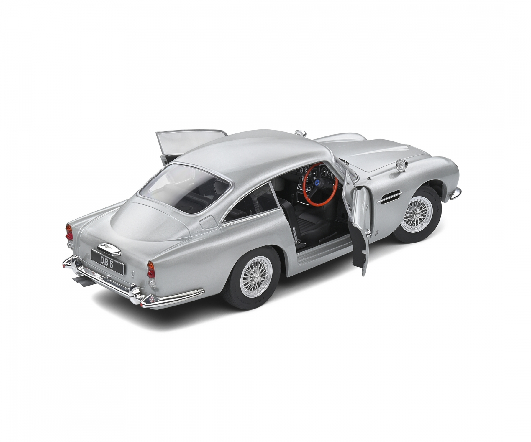 Ein silbernes Aston Martin DB5-Modell mit geöffneten Türen. Der Innenraum ist schwarz und das Lenkrad ist aus Holz. Das Auto ist auf Weiß isoliert.