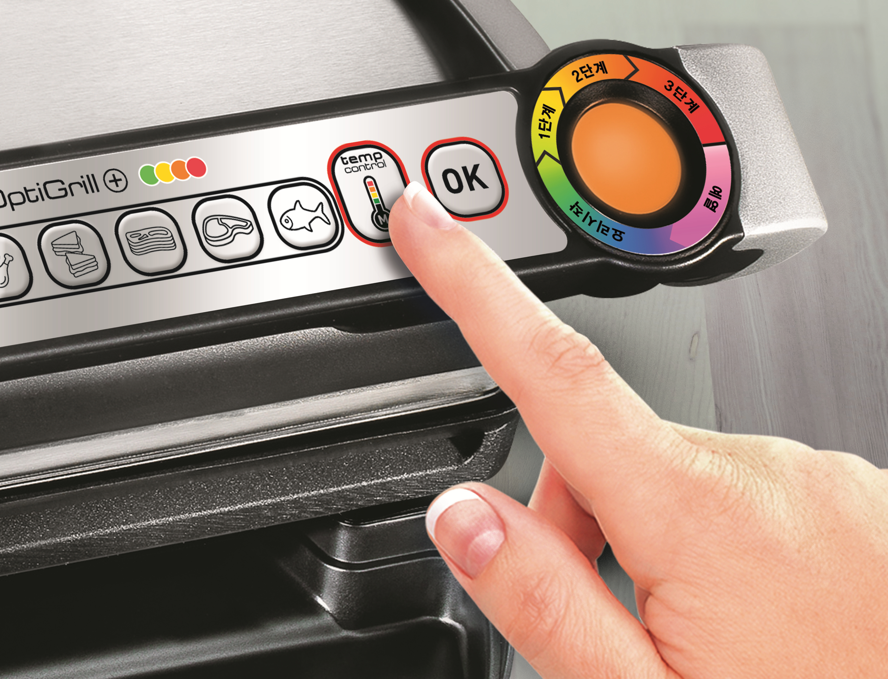 Eine Hand drückt die Taste 'Temperaturregelung' auf einem OptiGrill, Nahaufnahme der Bedienelemente.