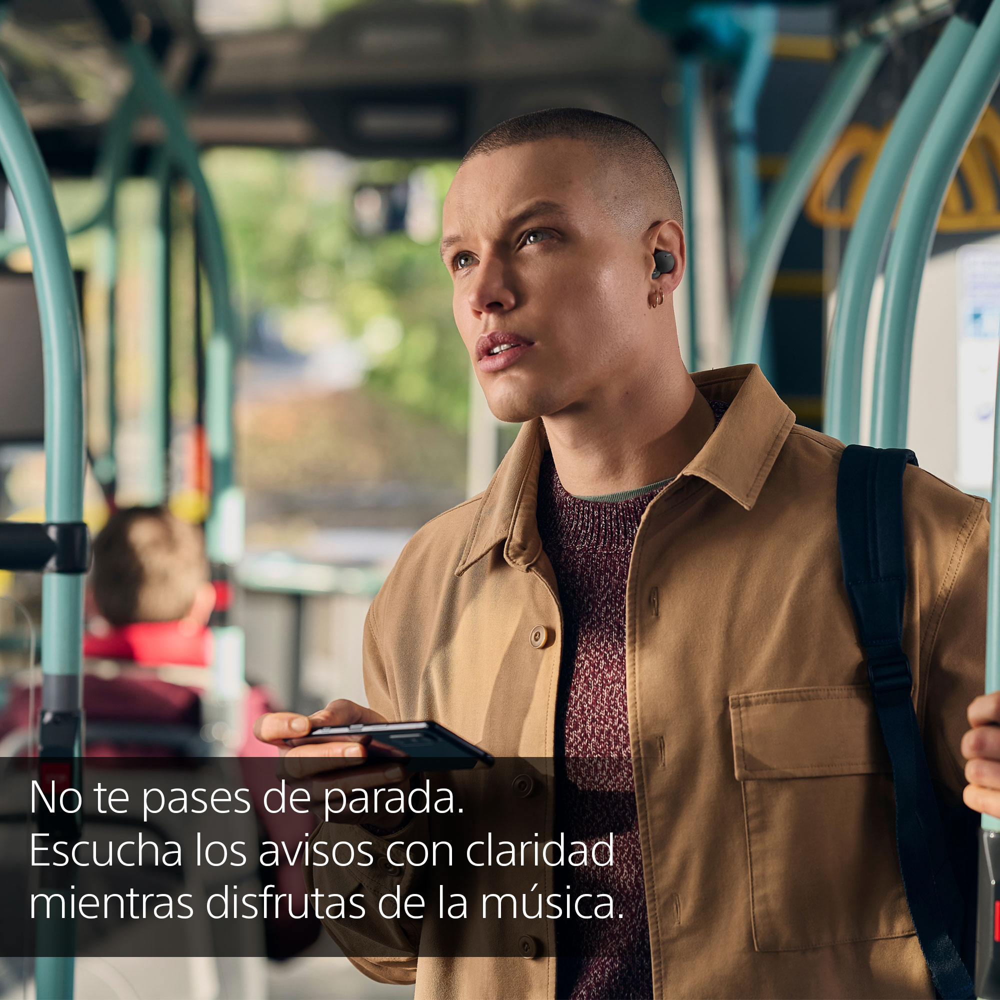 Un hombre en un autobús lleva auriculares y sostiene un teléfono. Superposición de texto en español.