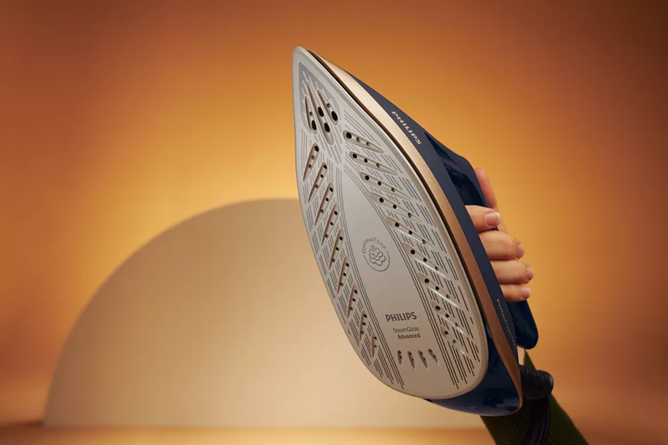 Közeli kép egy kék-arany vasalóról. A talp látható, a Philips márkával.