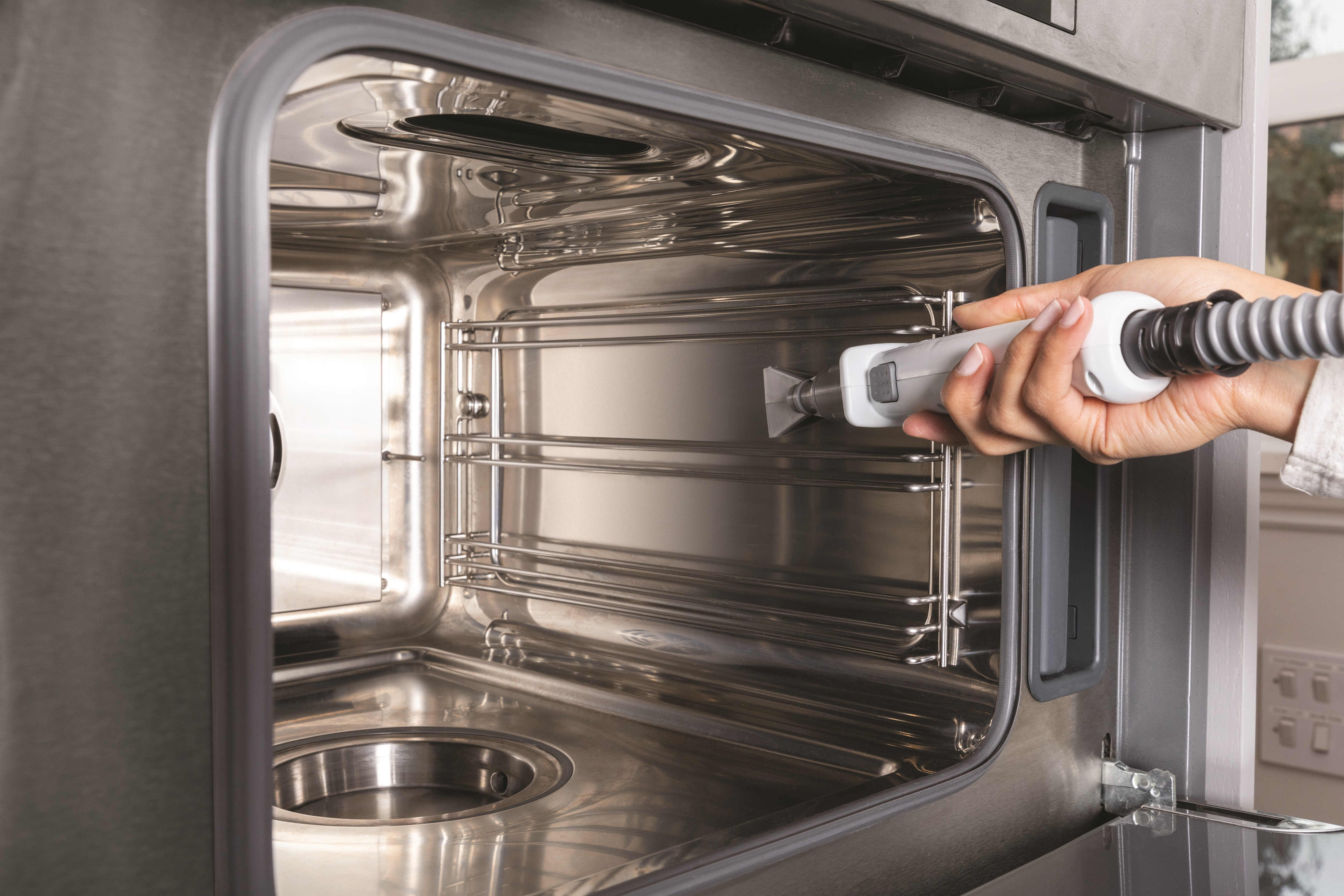 Binnenkant van een oven die wordt schoongemaakt met een stoomapparaat.