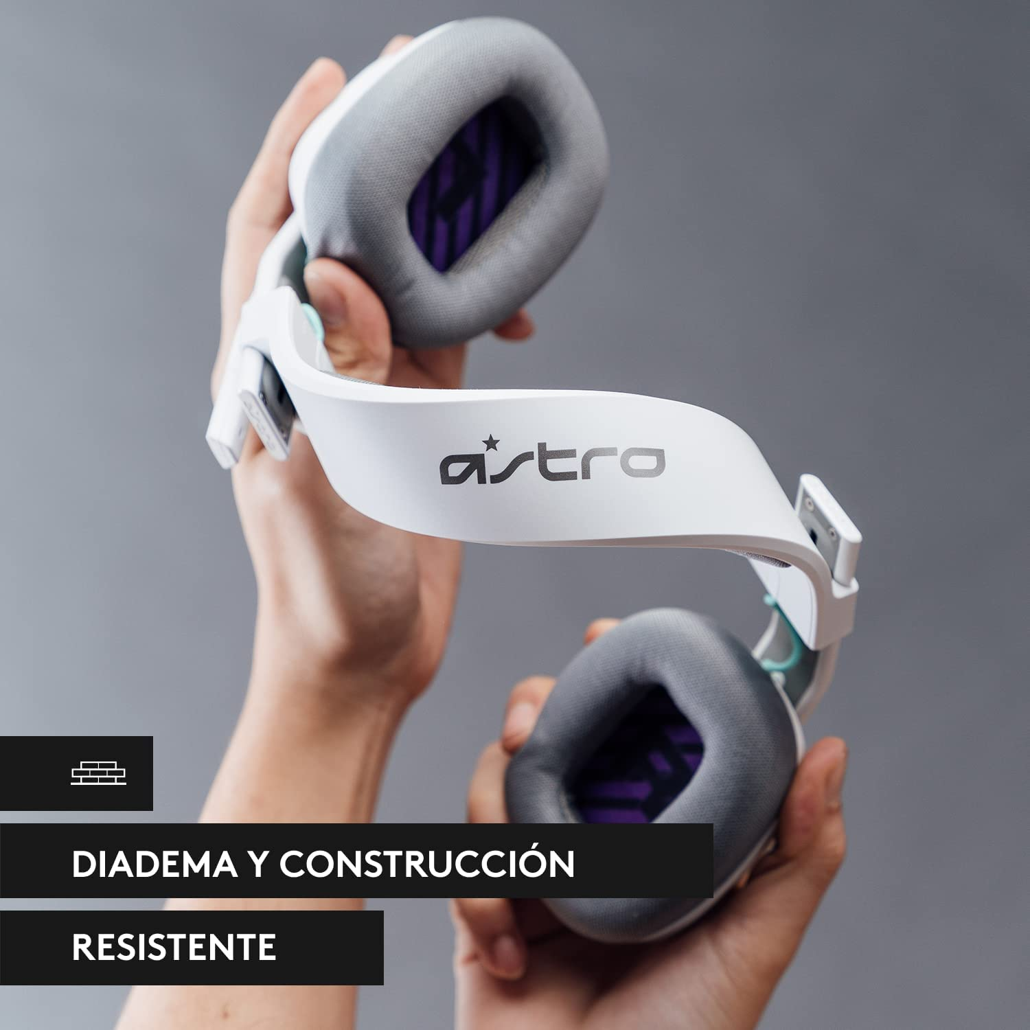 Auriculares Astro blancos sujetados por manos. El texto dice: Diadema y construcción resistente.