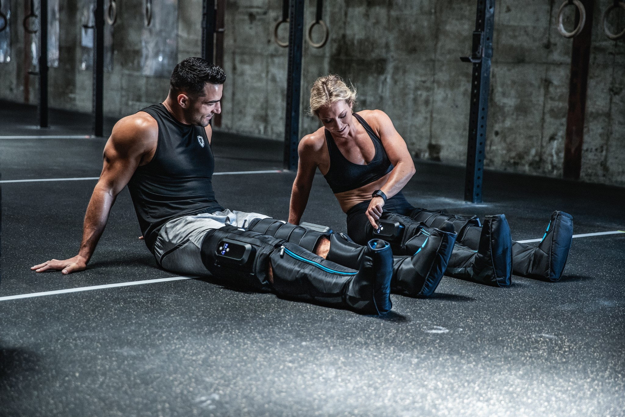 Zwei Personen in einem Fitnessstudio mit Bein-Kompressionsärmeln.