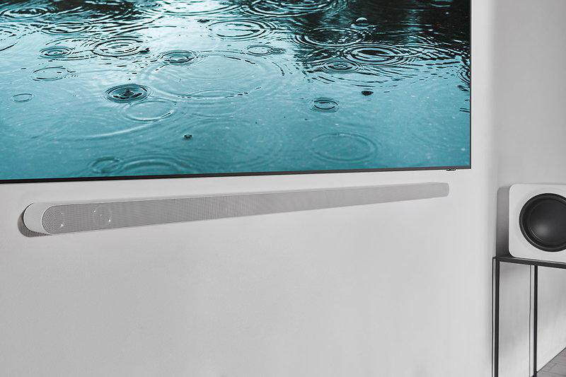 Ein Fernseher an einer weißen Wand mit einer Soundbar darunter, die eine regnerische Szene zeigt.