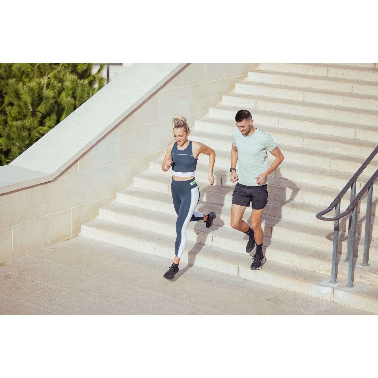 Dos personas corriendo por una escalera. Ambos llevan ropa deportiva.