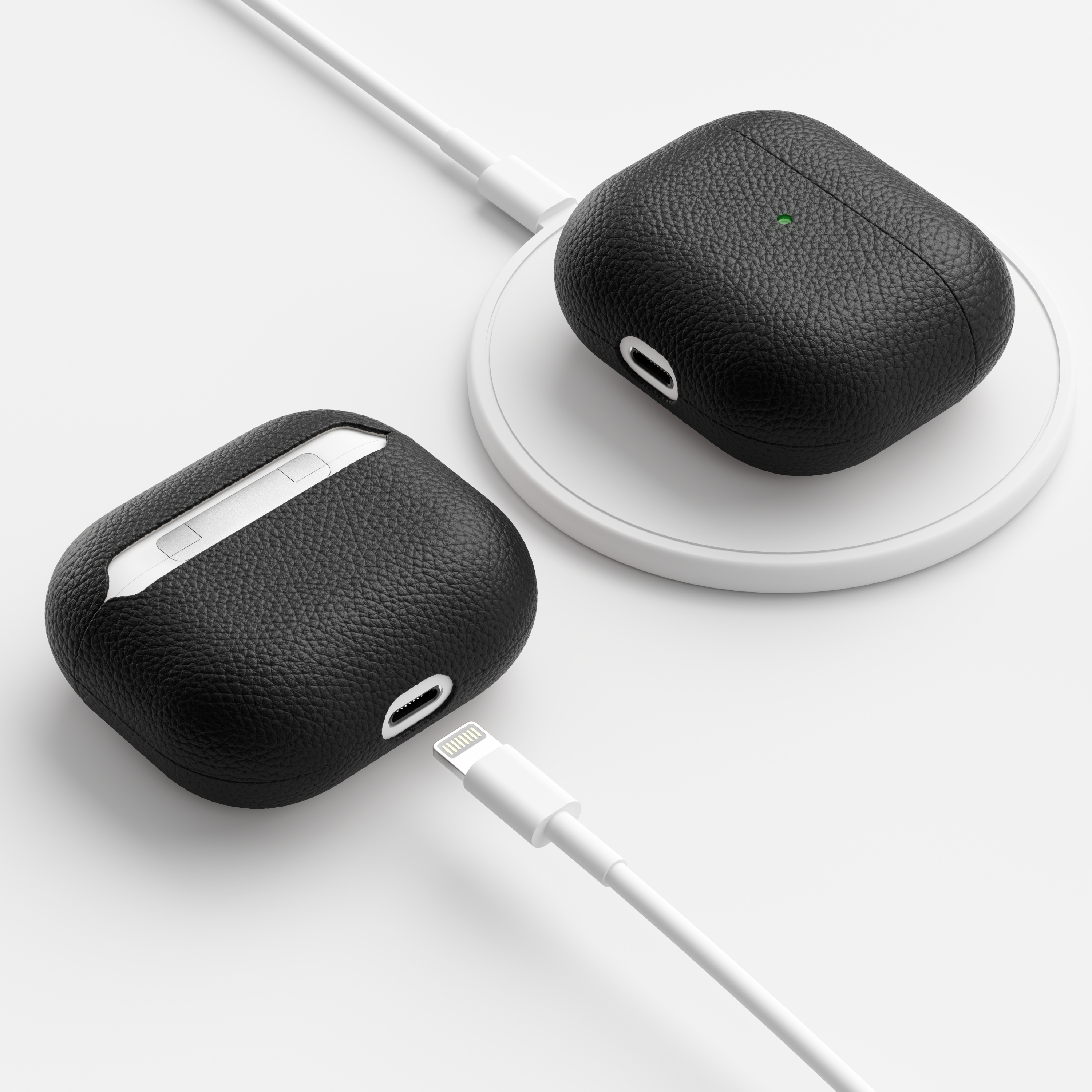 Zwei schwarze Leder-AirPods Pro-Hüllen, eine lädt auf einem weißen Pad, die andere mit Ladekabel.