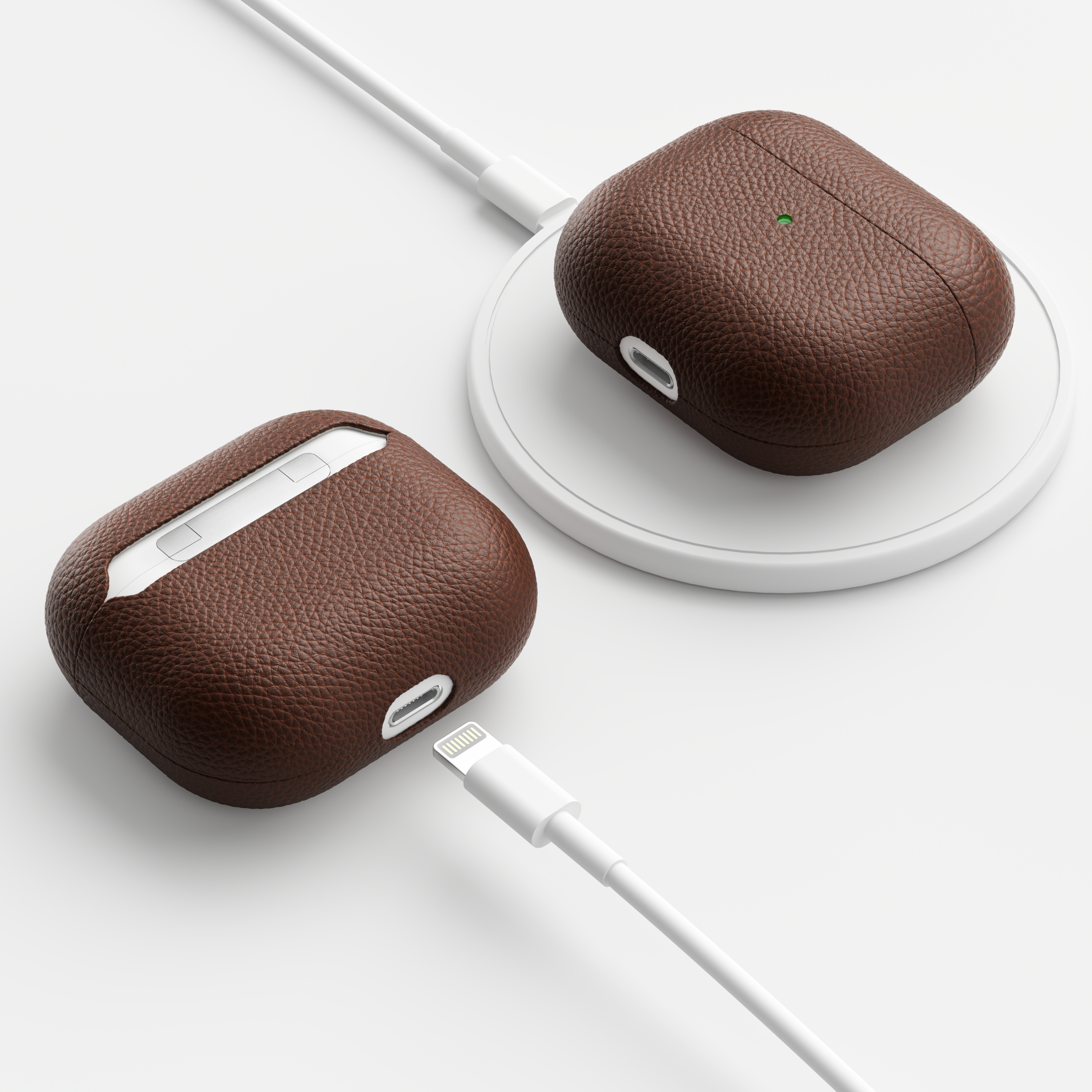 Zwei braune Leder-AirPod-Hüllen, eine auf einem Ladepad mit weißem Kabel, die andere mit Kabel.