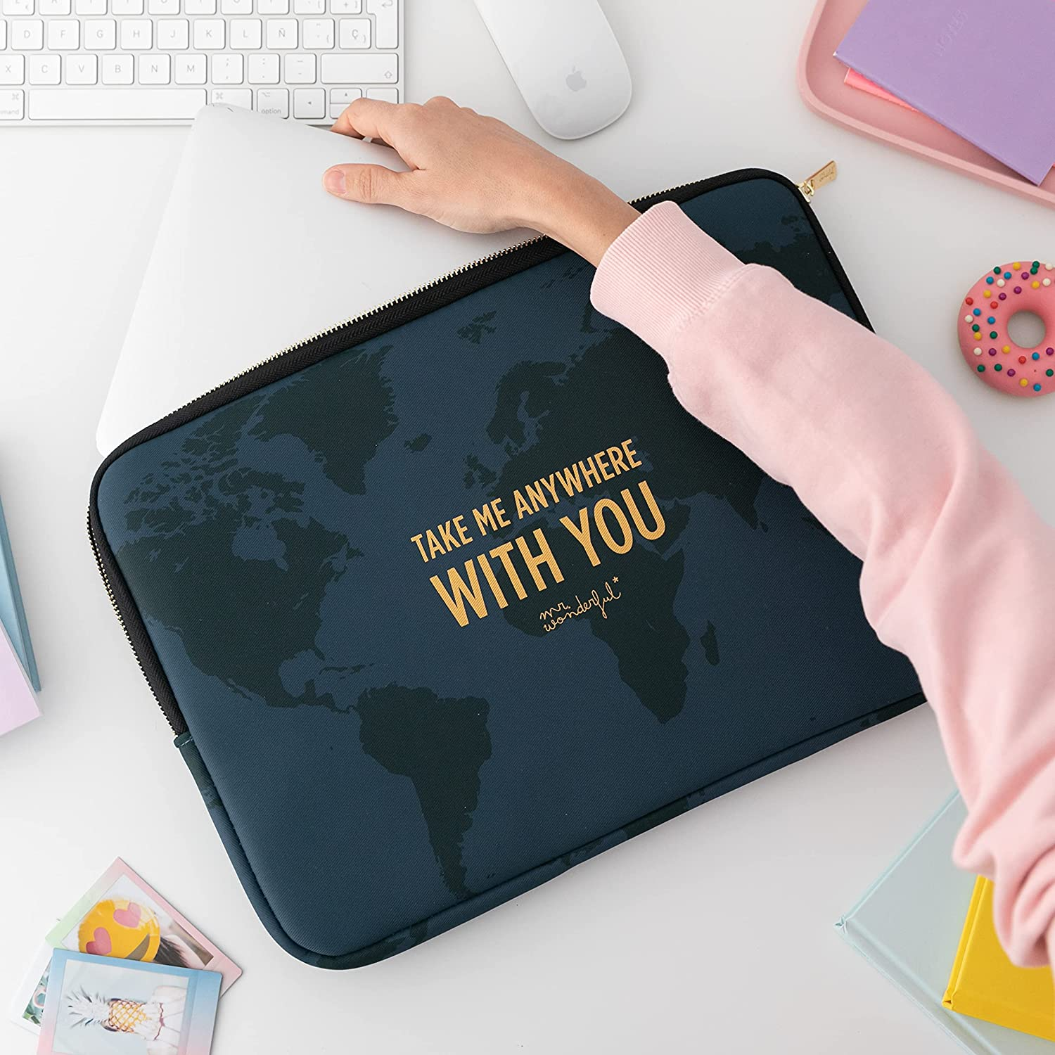Una mano coloca un portátil en una funda azul marino. La funda tiene un diseño de mapa del mundo.