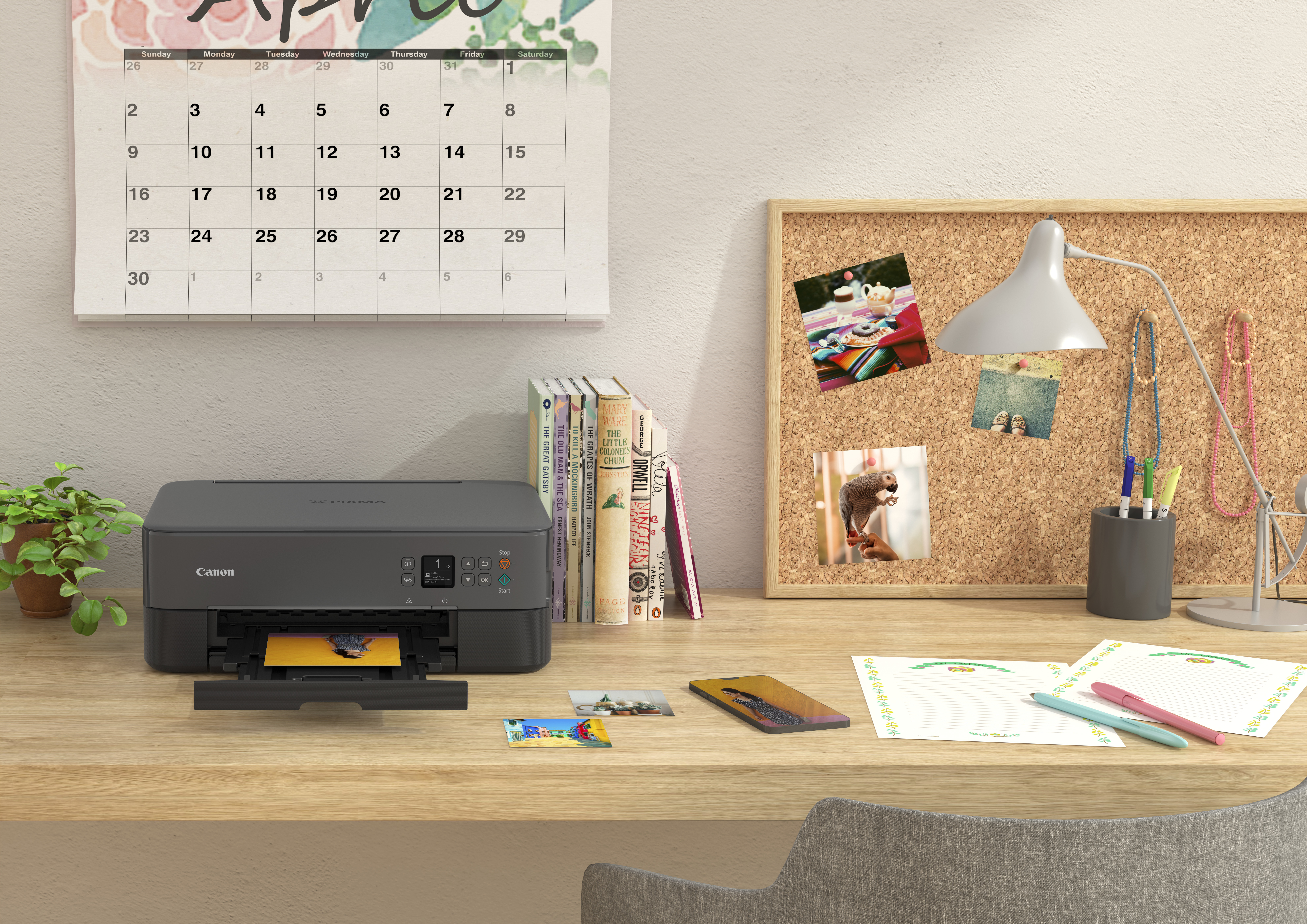 Ein Schreibtisch mit Drucker, Kalender, Büchern und Zubehör, mit Fenster im Hintergrund.