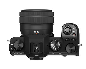 Bovenaanzicht van een zwarte camera met lens, met de draaiknoppen en bedieningselementen.