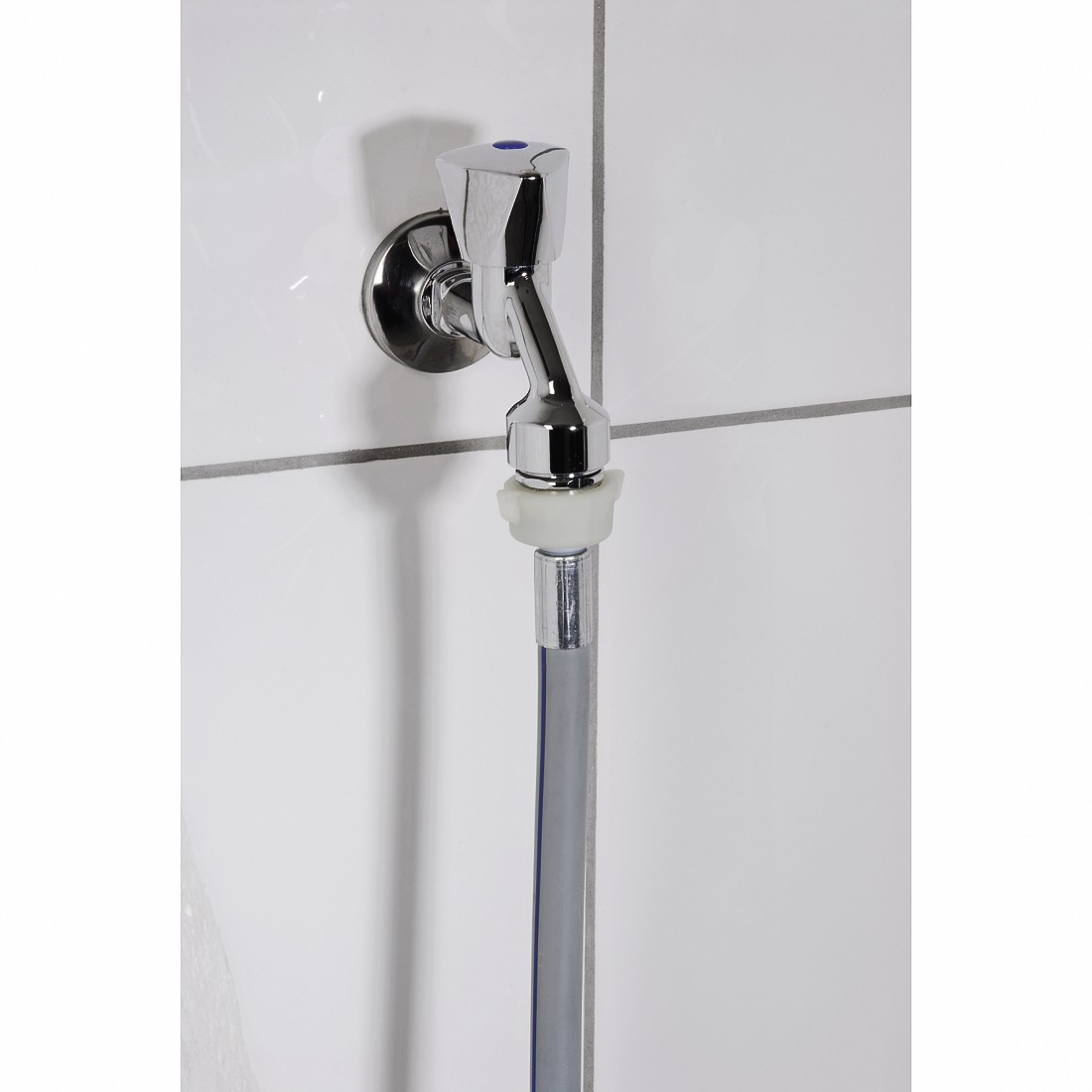 Un robinet chromé avec un tuyau gris attaché. Le robinet est monté sur un mur carrelé blanc.