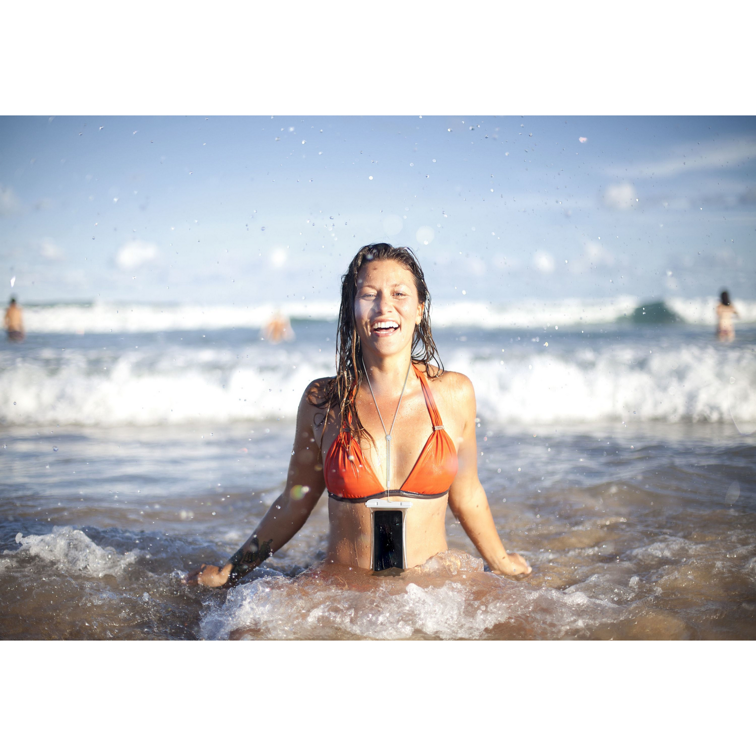 Una mujer en bikini naranja en el mar, con un collar para teléfono.