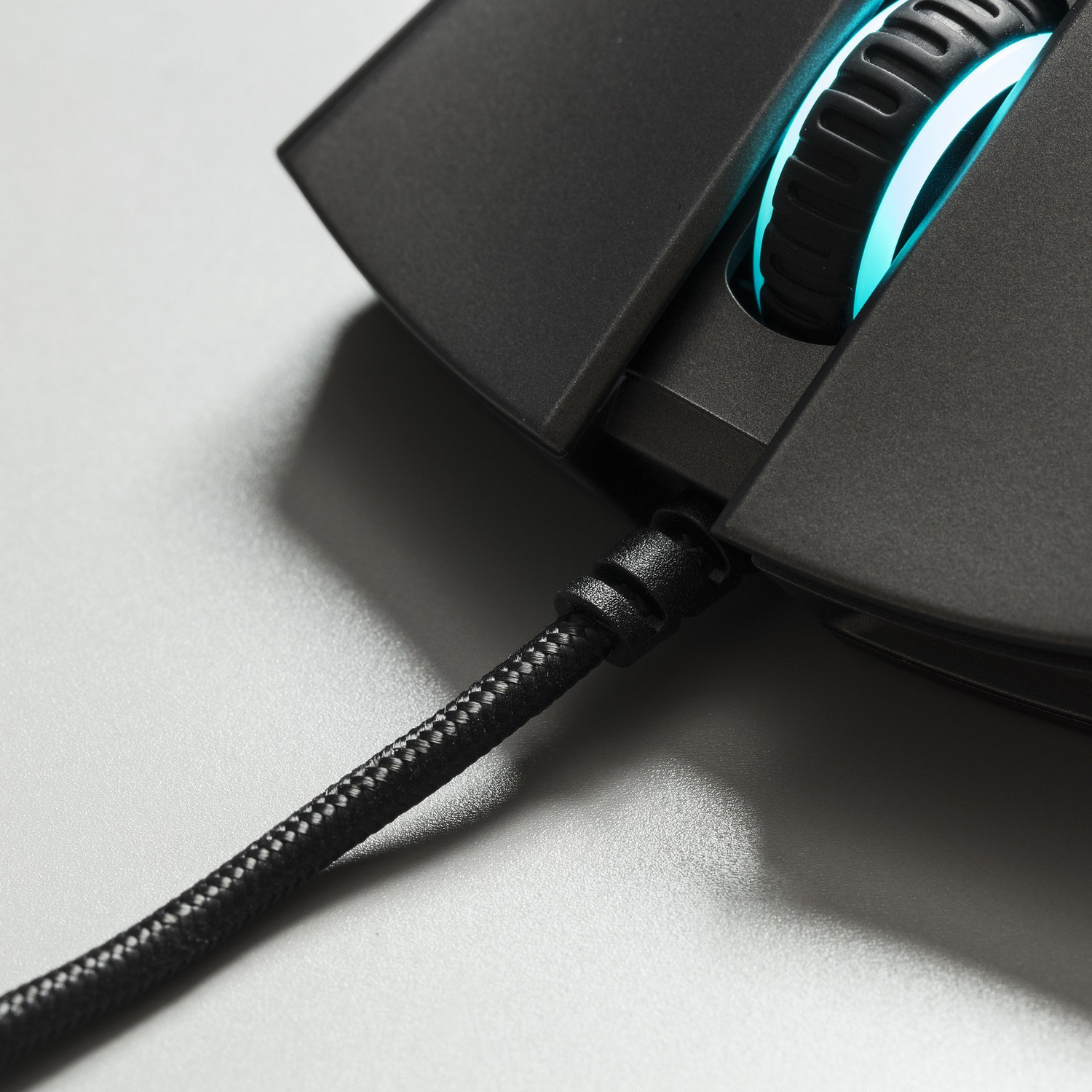 Primer plano de un ratón gaming negro, con cable trenzado y rueda de desplazamiento brillante.