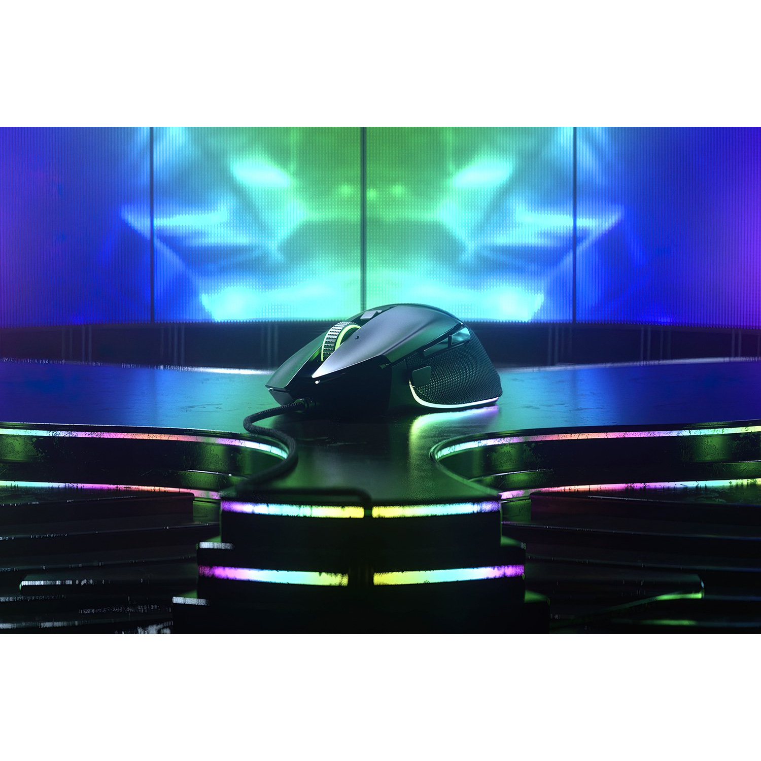 Ratón gaming negro sobre escenario iluminado, con luces de fondo coloridas.