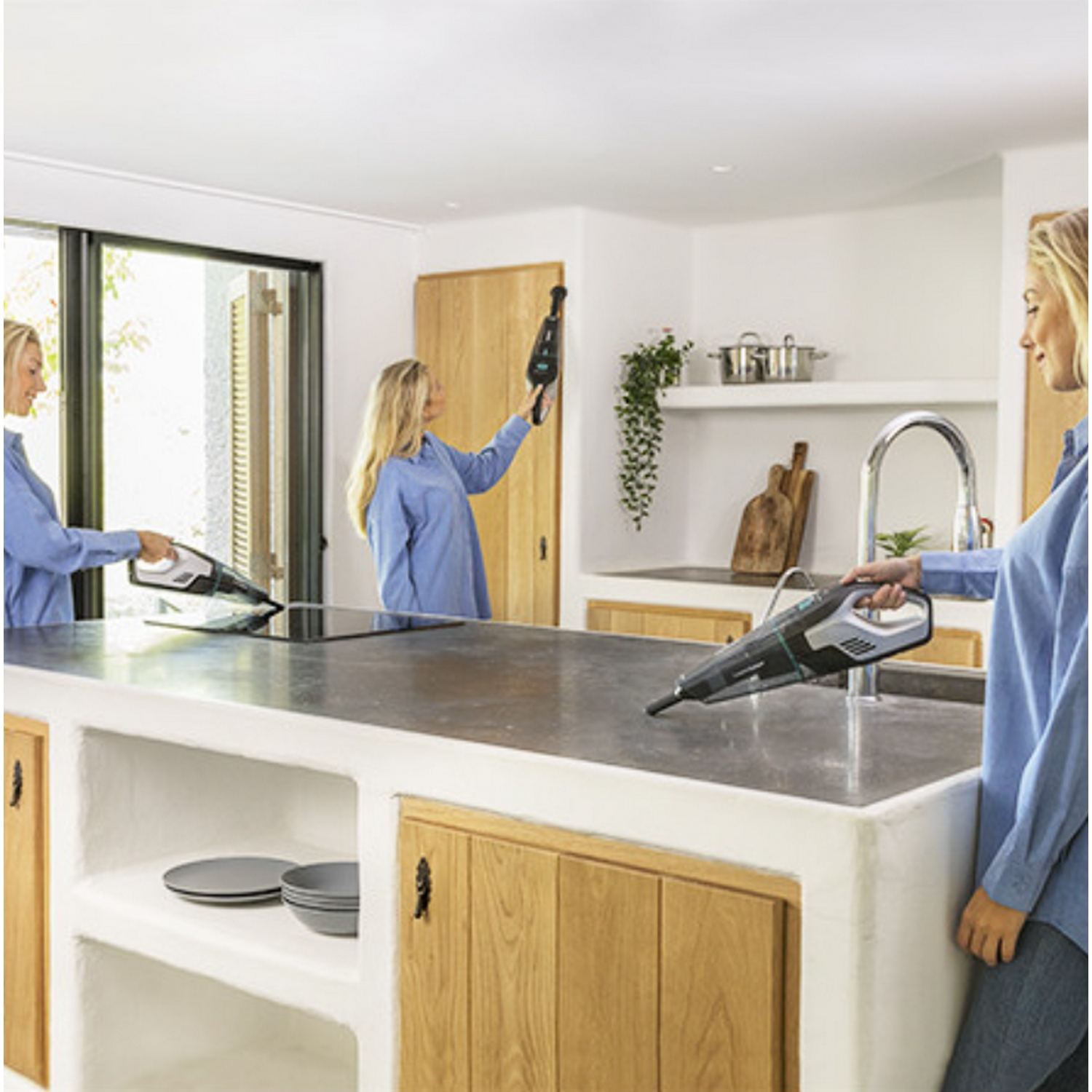 Tres mujeres en una cocina, una usando una aspiradora.