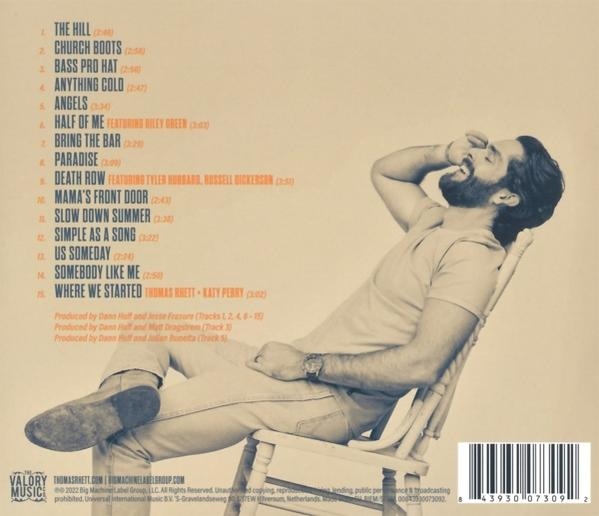 Mann sitzt auf einem Stuhl, lehnt sich zurück und hält seinen Kopf, Albumcover im Hintergrund.