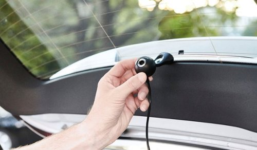 Une main tenant une caméra de voiture noire montée sur la vitre arrière.