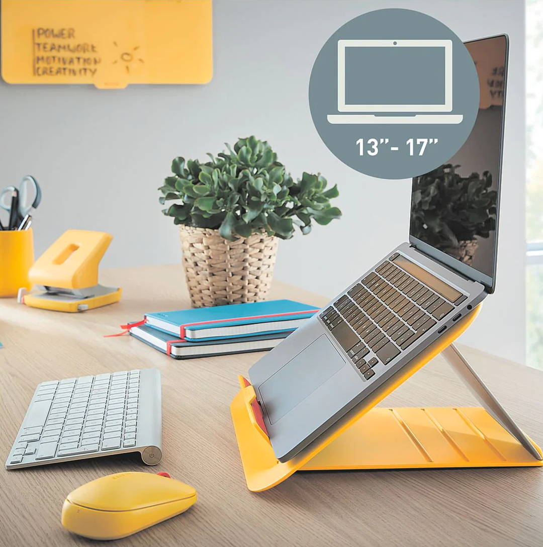 Egy laptop sárga állványon, billentyűzettel és egérrel. A háttérben egy növény.
