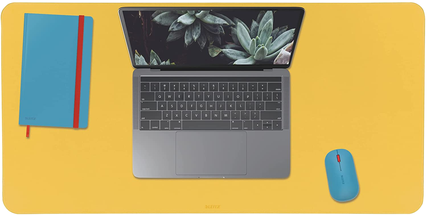 Nyitott laptop, kék jegyzetfüzet, kék egér, sárga felület. Asztali beállítás technológiával.