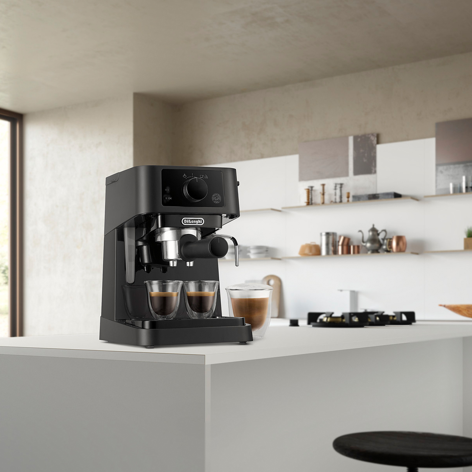 Macchina per caffè espresso nera con due tazze di caffè su un bancone bianco, sfondo cucina.