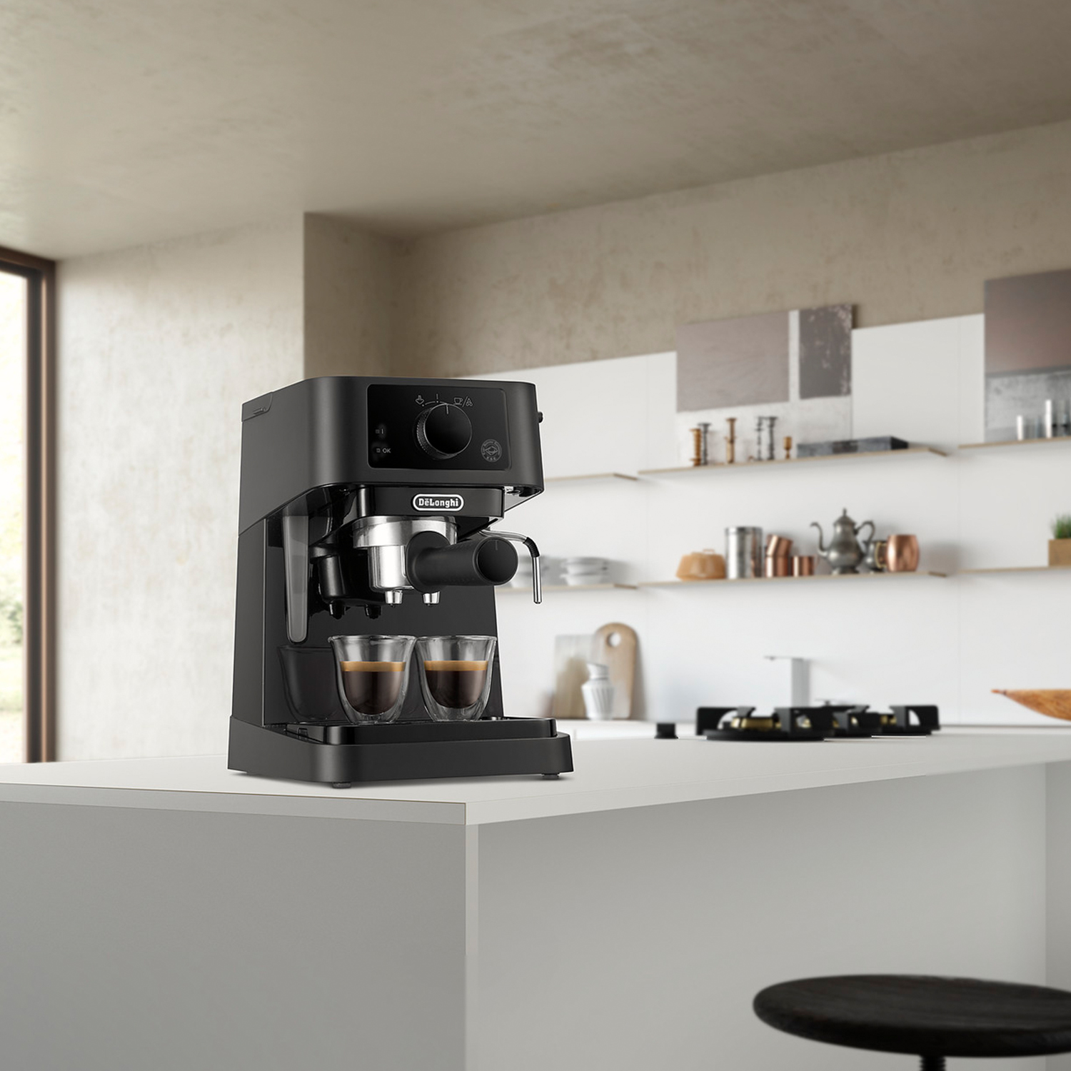 Macchina per caffè espresso nera su un piano di lavoro bianco. Due bicchieri con caffè. Sfondo cucina.