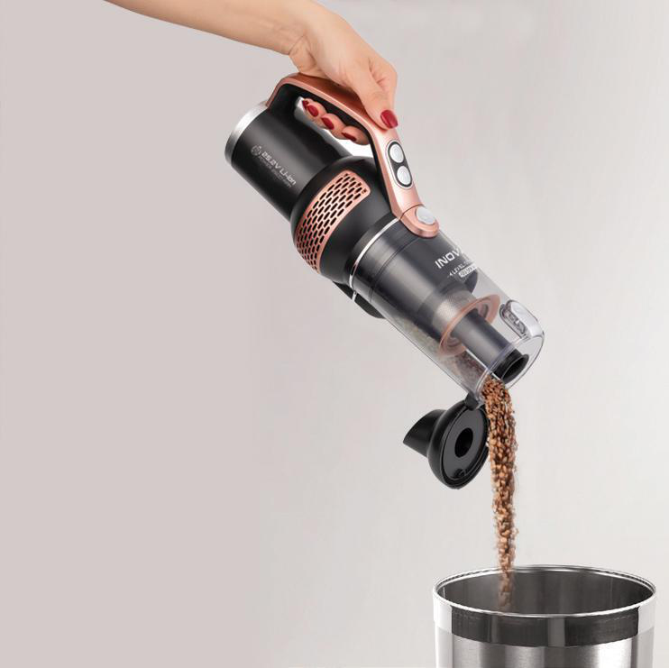 Eine Hand, die Kaffeebohnen in einen Staubsauger gießt.