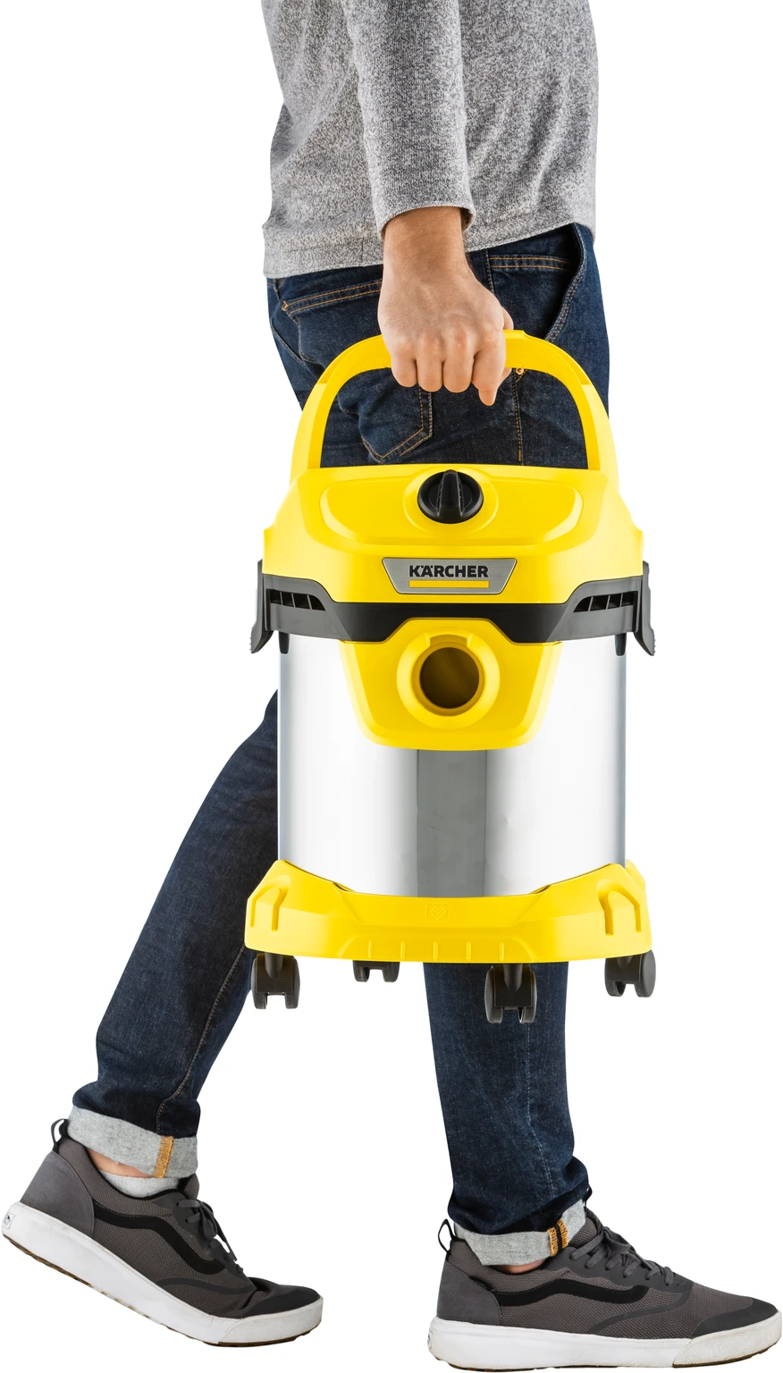 Person carrying a yellow and silver vacuum cleaner. Jeans and sneakers.