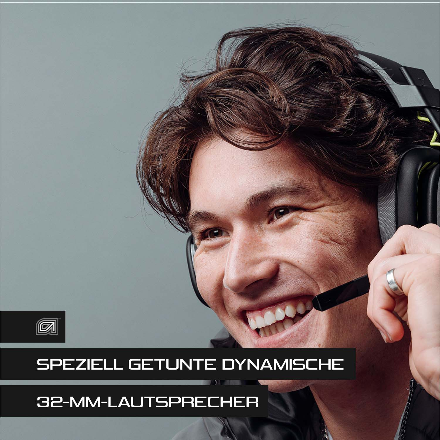 Mann lächelt mit Gaming-Headset, Nahaufnahme. Grauer Hintergrund.
