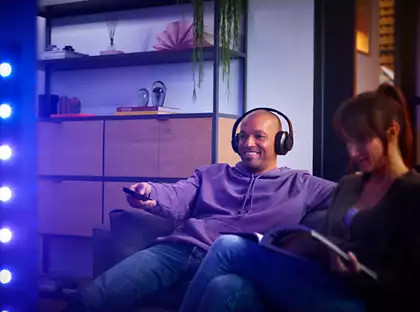 Homme avec casque et femme regardant la télévision sur un canapé. Lumière bleue.