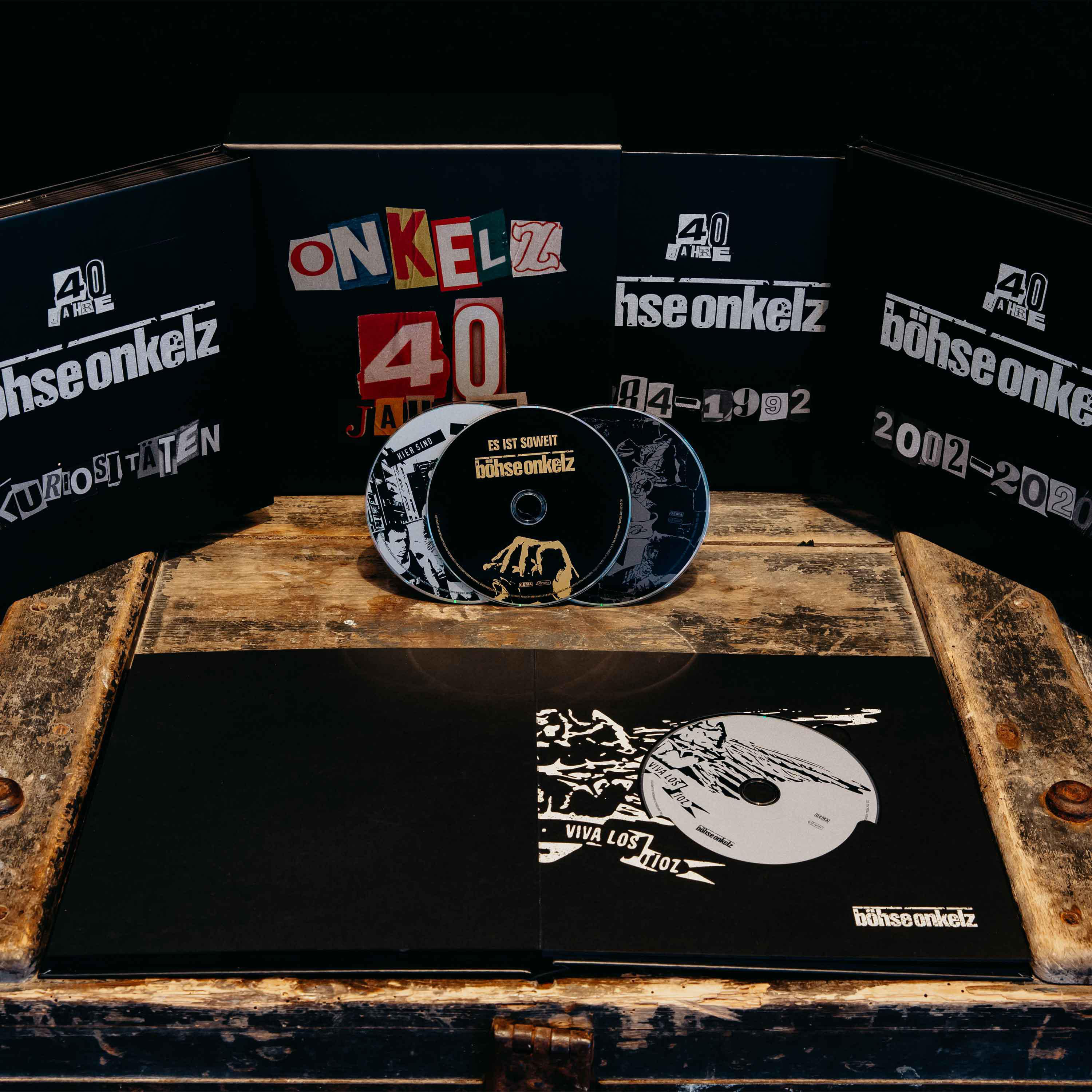 CD-Set. CDs mit Text und Logo, in einer schwarzen Box auf Holzoberfläche.