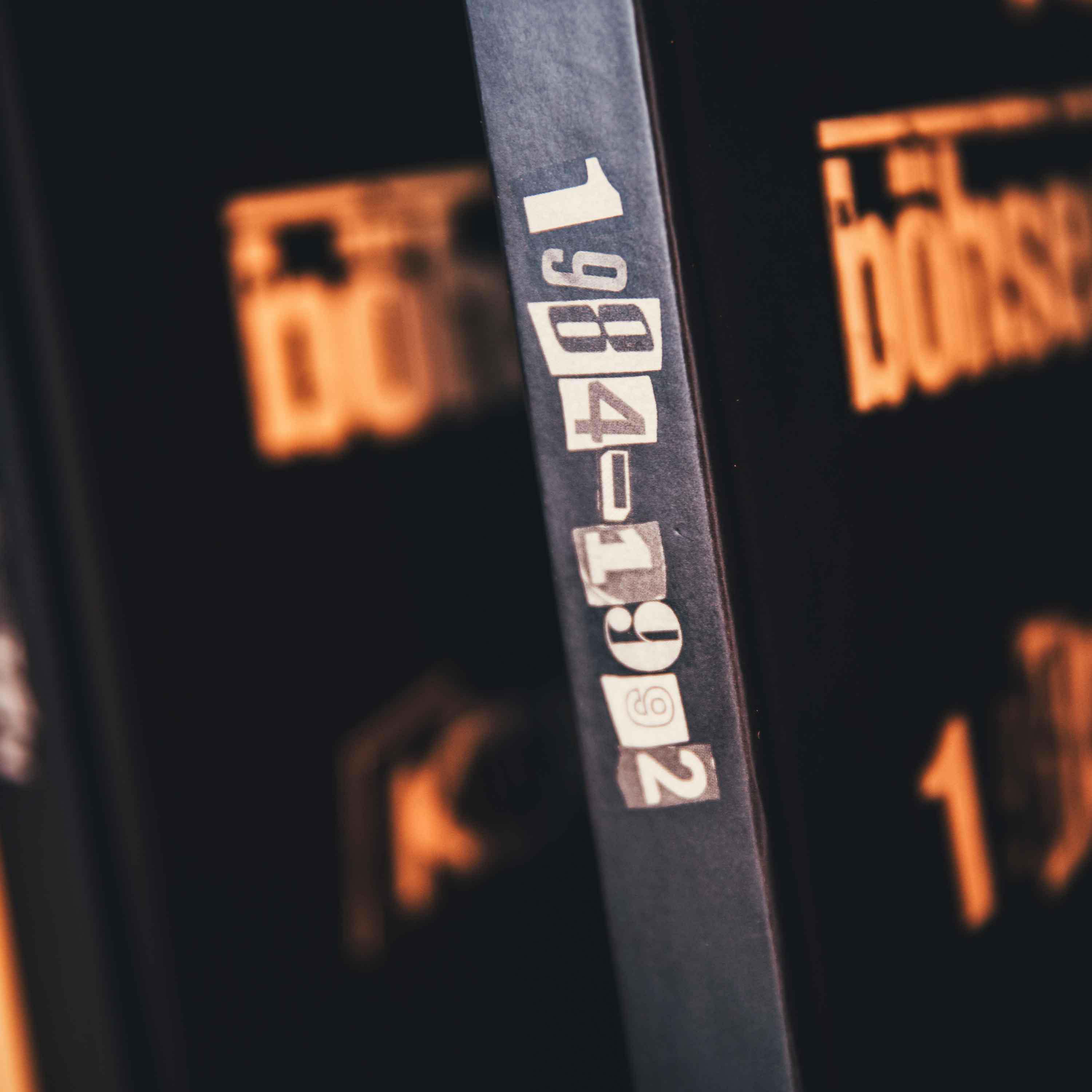 Nahaufnahme eines Buchrückens mit der Aufschrift '1984-1992'. Der Rücken ist dunkel.
