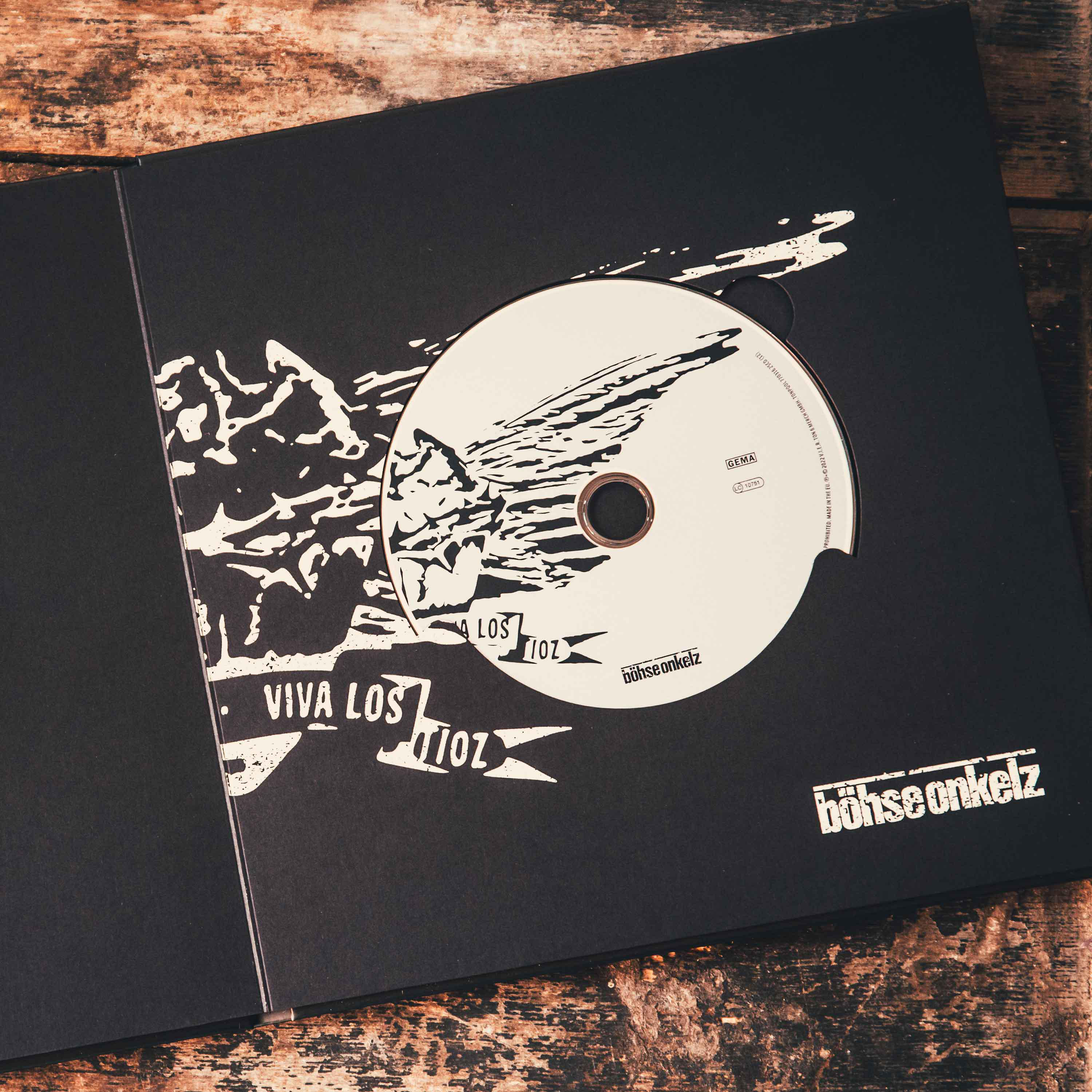 Schwarze CD-Hülle mit einer Disc und einem Logo auf Holzoberfläche.