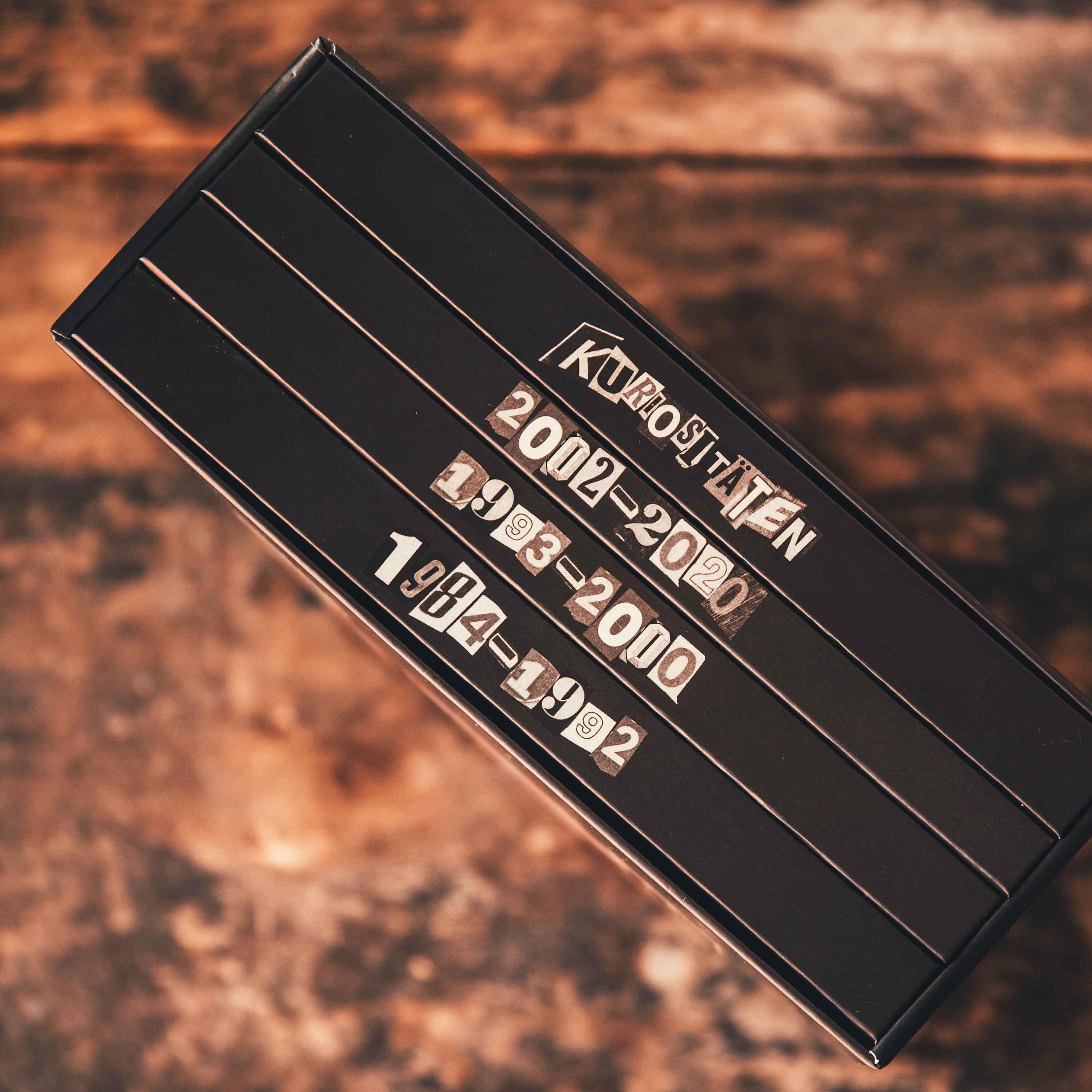 Schwarze Box mit weißem Text. Der Text lautet 'Kuroshitsuji' und die Jahre 2002-2020, 1993-2000, 1984-1992.