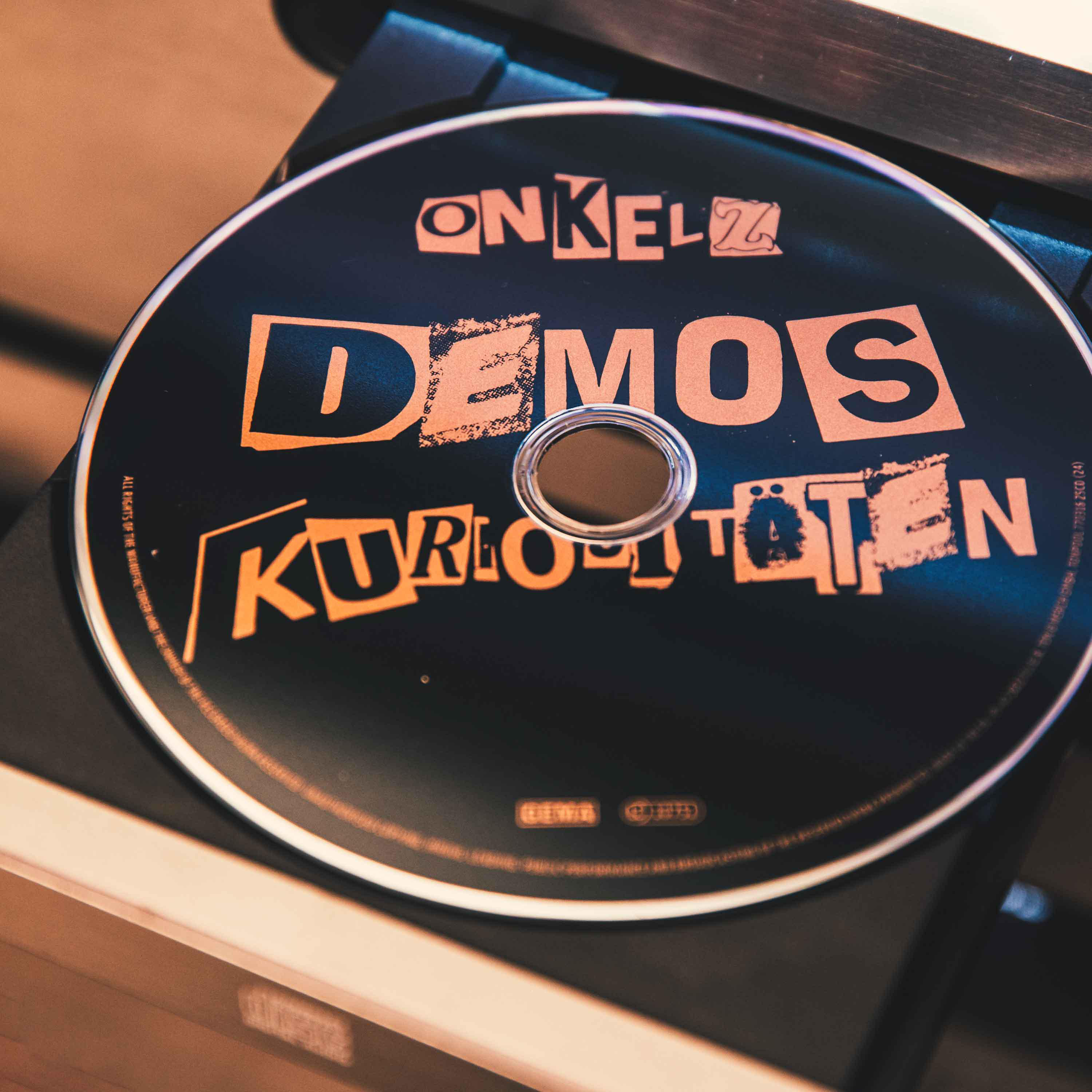 Eine schwarze CD mit orangefarbenem Text, die auf einem Plattenspieler liegt.