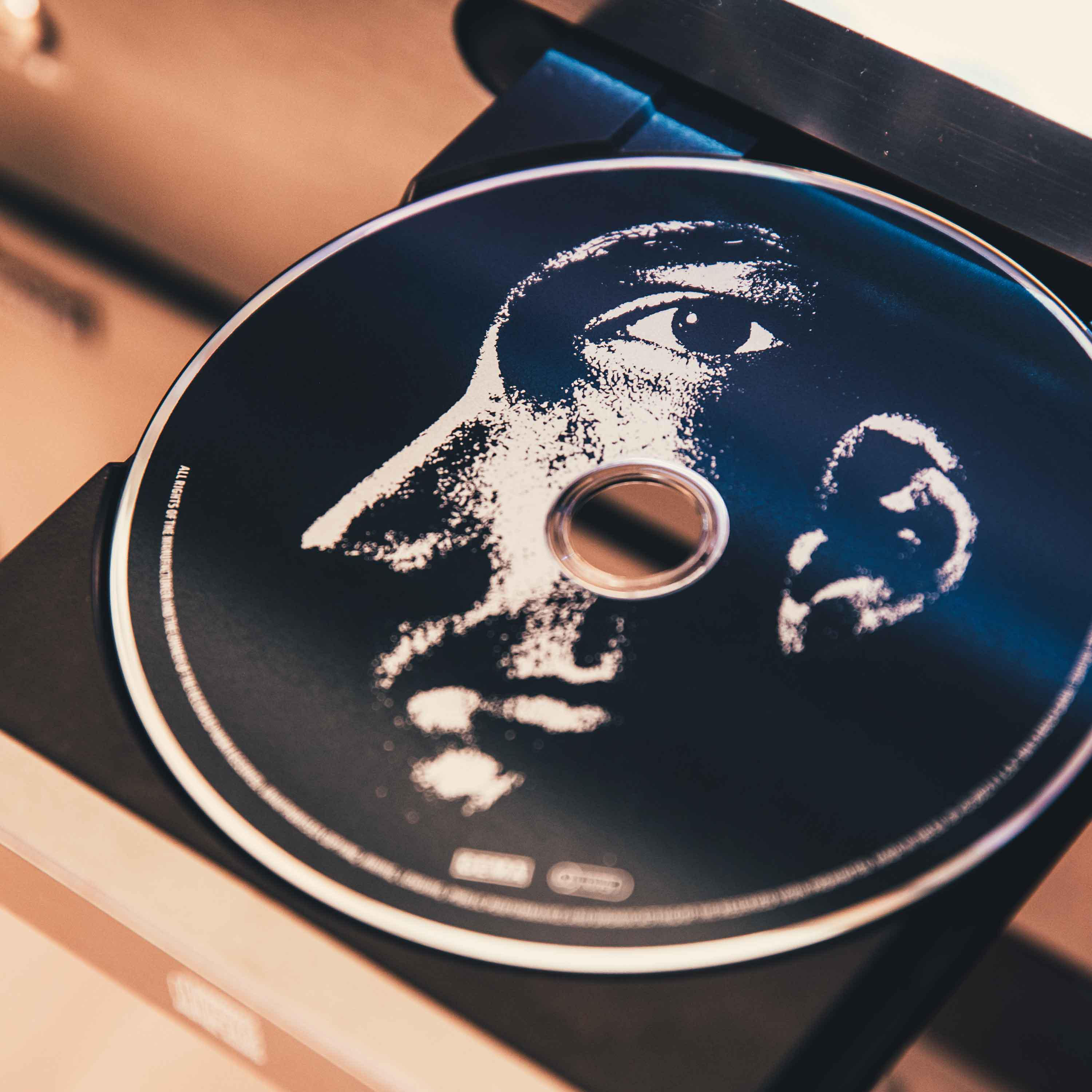 CD im Player mit Gesichts-Art. Bild eines Gesichts auf der Disc. Schwarz und Braun.